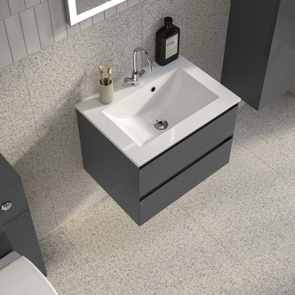 Modern bathroom sink with grey cabinetry, a beige toothbrush holder, and bathroom essentials including soap and toiletries on a textured wall.
