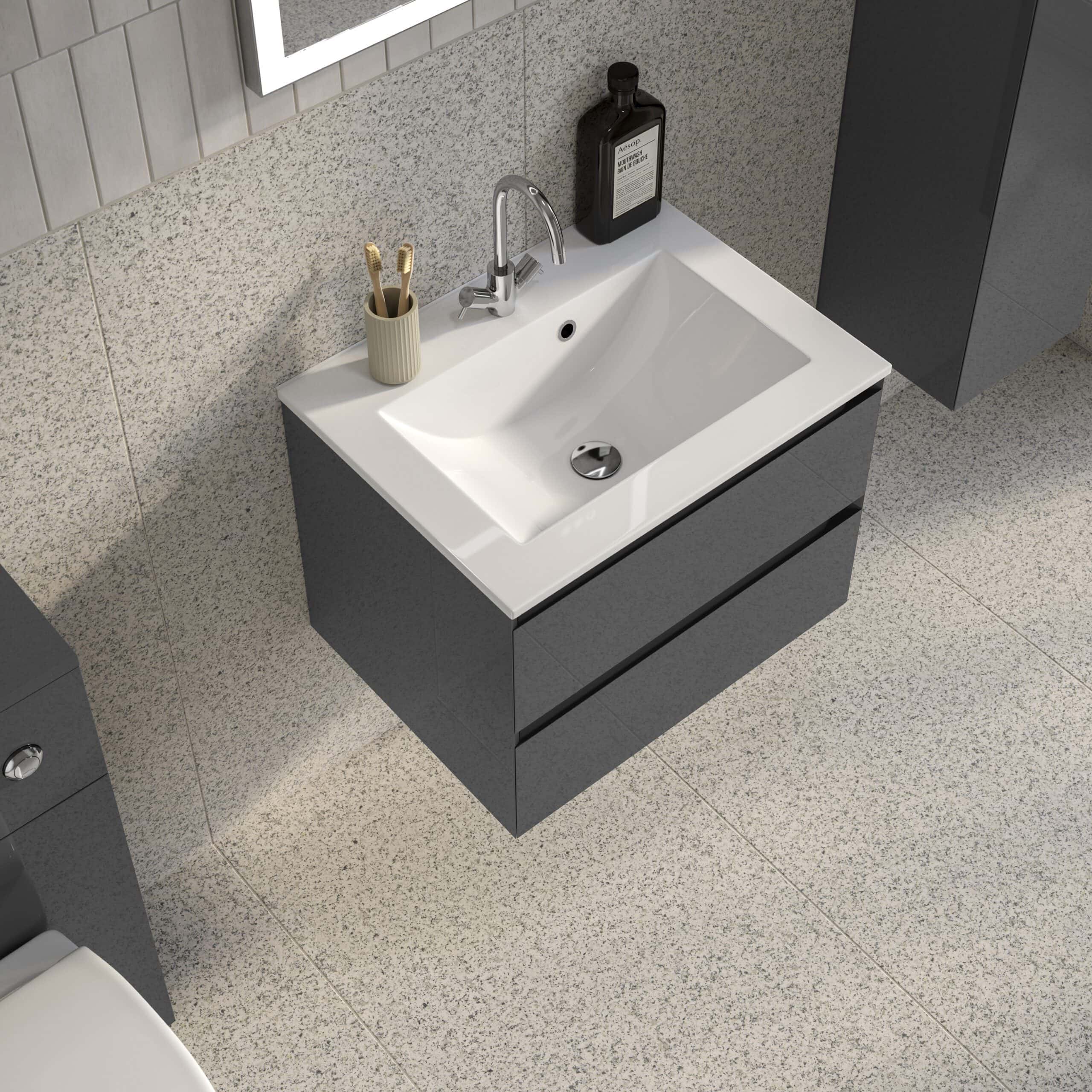 Modern bathroom sink with grey cabinetry, a beige toothbrush holder, and bathroom essentials including soap and toiletries on a textured wall.