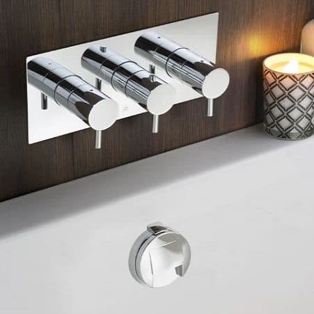 Sleek modern chrome bathroom thermostatic shower valve with three controls, installed on a wooden wall with a decorative candle nearby.