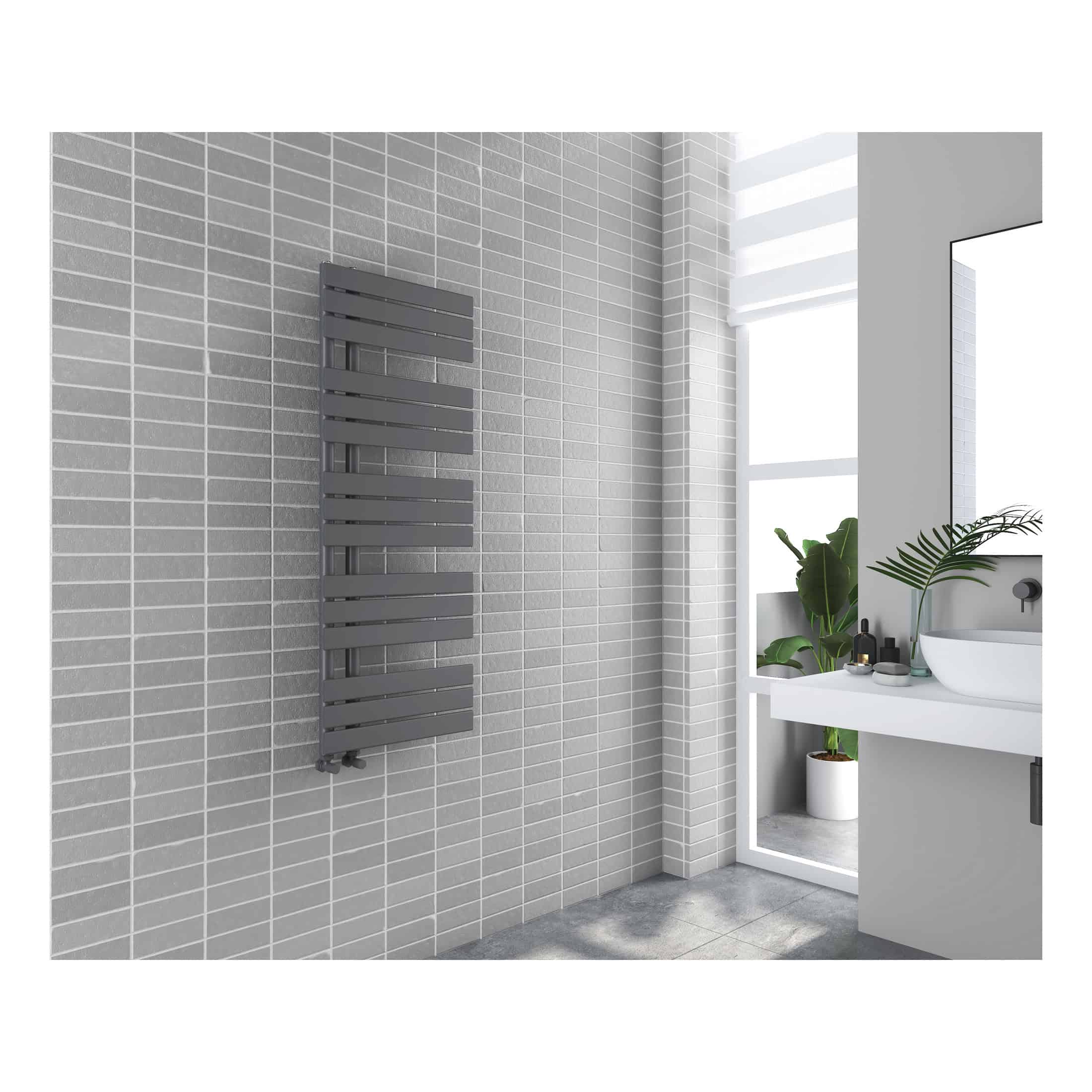 Vertical black radiator in modern grey tiled bathroom with white sink and potted plant, stylish bathroom heating solution, contemporary design, bathroom decor, Bubly Bathrooms UK.