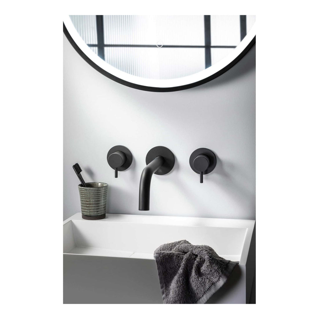 Modern black bathroom tap set with wall-mounted controls and a round mirror, ideal for contemporary bathroom designs.