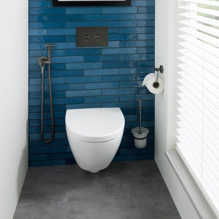 Modern blue tiled bathroom with sleek wall-mounted toilet and accessories, bright natural light, minimalistic design, ideal for contemporary bathroom decor, showcasing Bubly Bathrooms' stylish and functional fixtures.