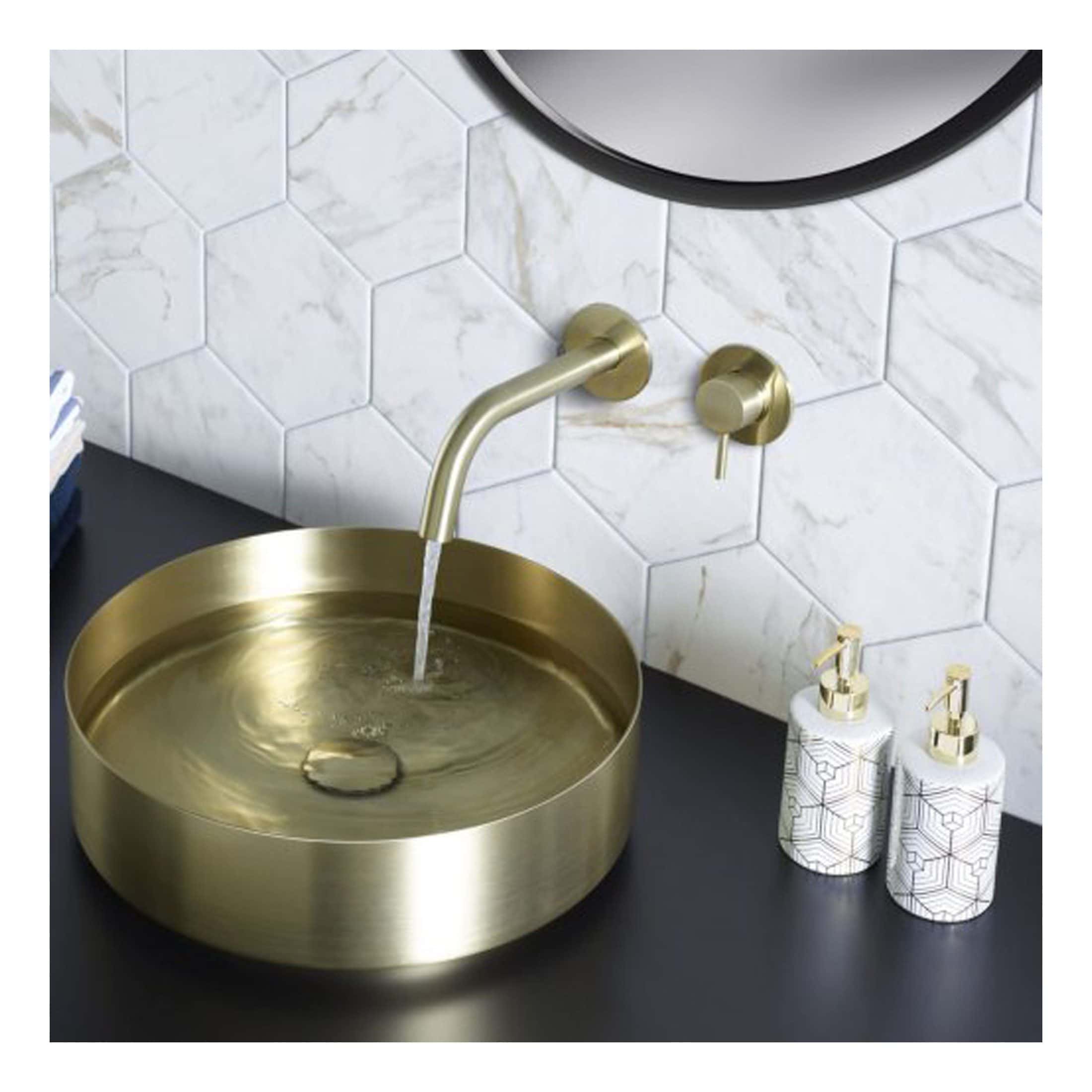 Sleek gold bathroom sink with a modern round design, wall-mounted faucet, and elegant hexagon marble tiles on the wall, creating a luxurious and stylish bathroom space.