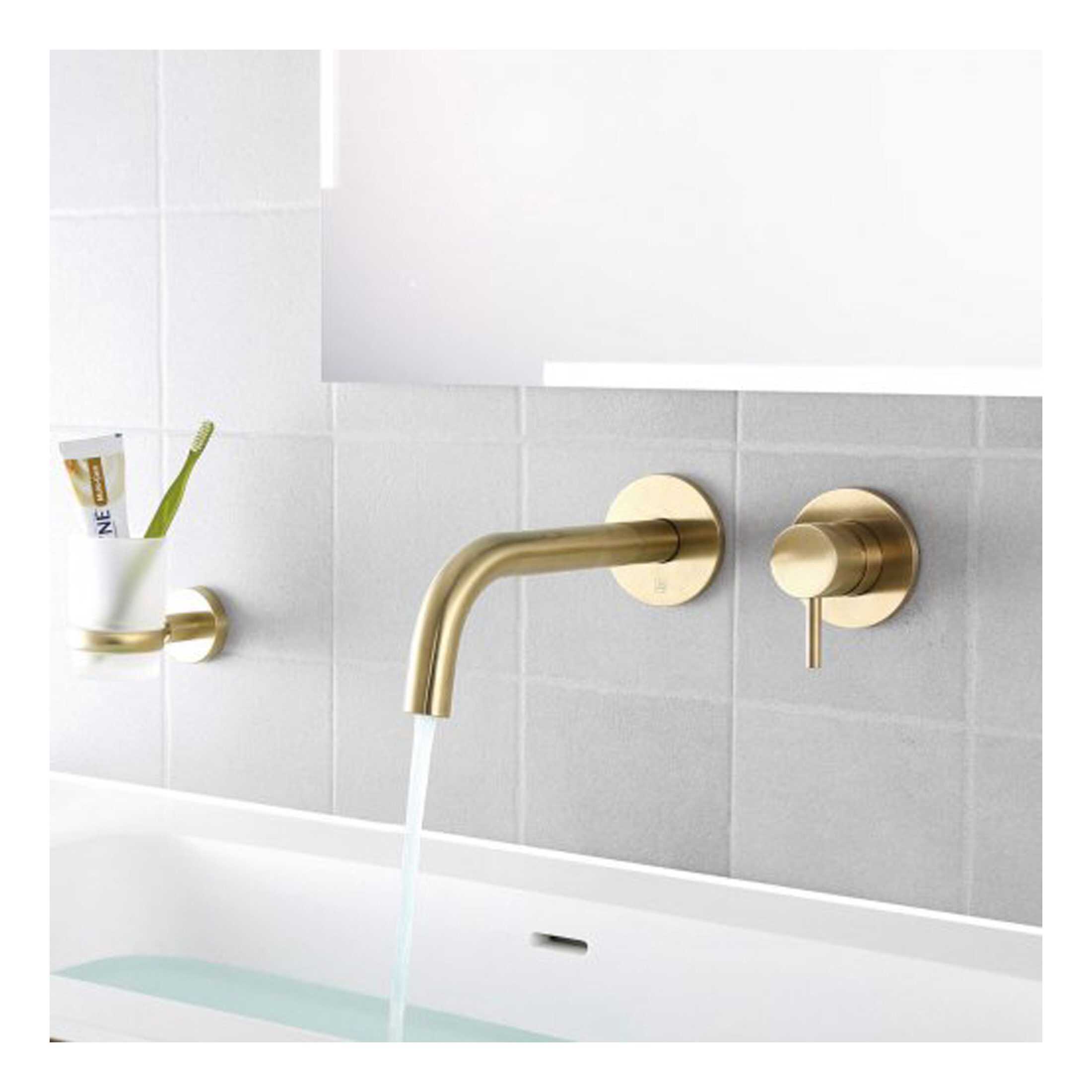 Sleek gold wall-mounted bathroom tap with matching control handle, modern bathroom accessories, and white tiled background, perfect for contemporary style bathrooms.