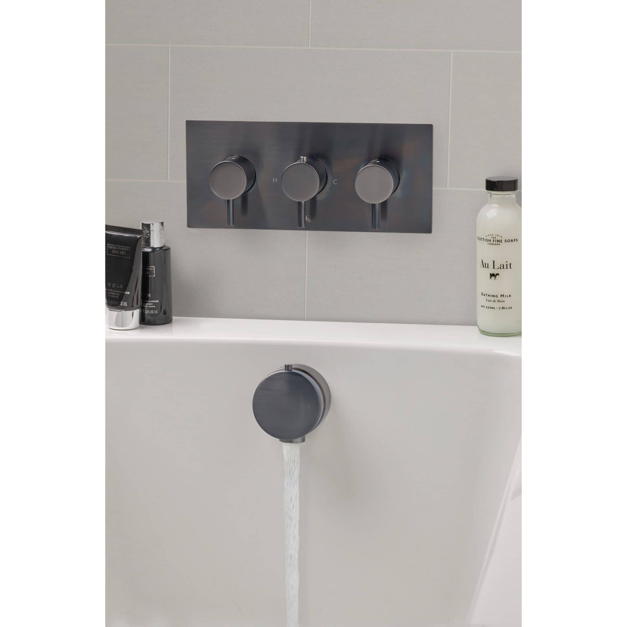 Sleek modern bathtub with stainless steel control panel and mounted faucet, featuring bath amenities and a minimalistic design perfect for contemporary bathroom spaces.