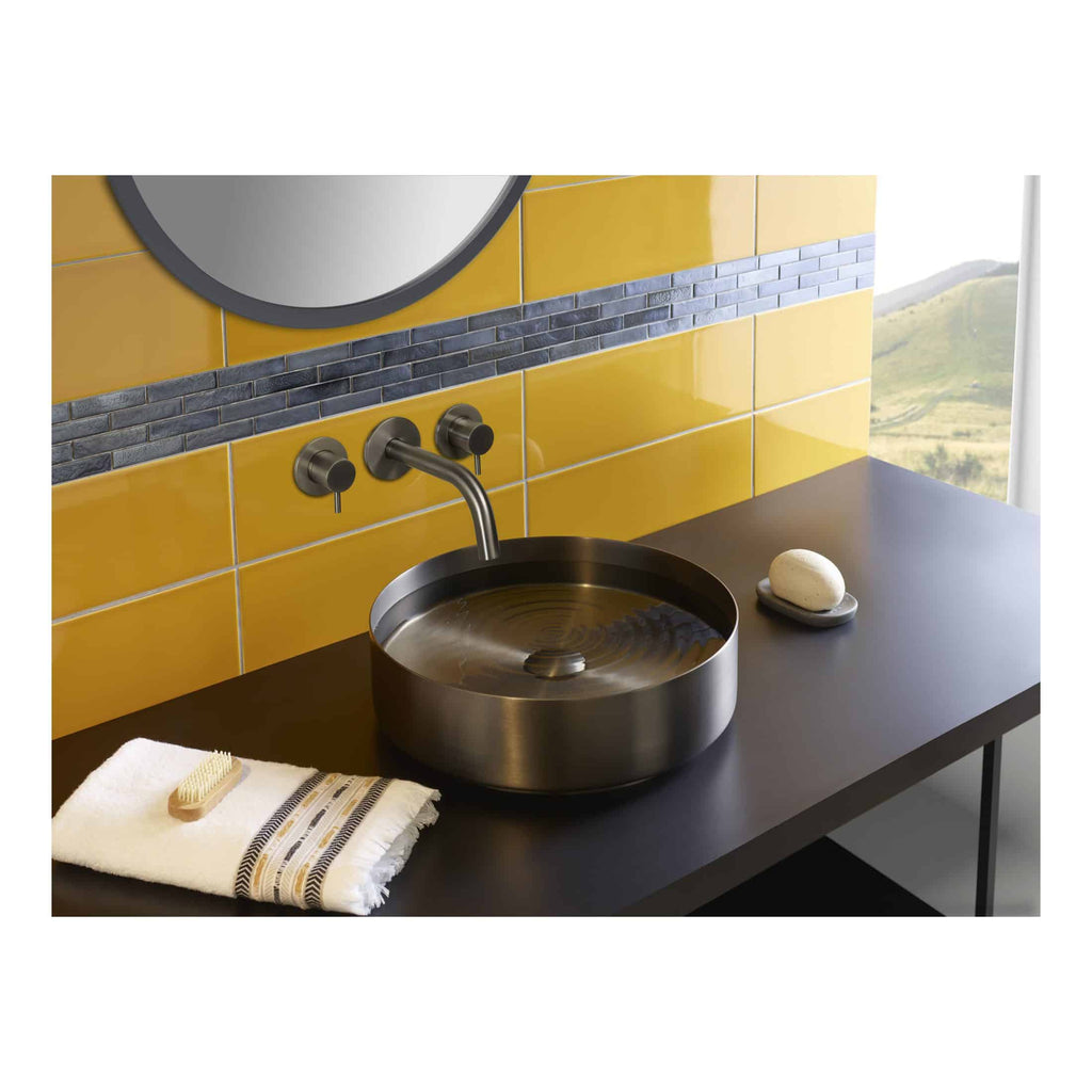 Sleek modern bathroom sink with a stainless steel basin, set against a vibrant yellow tiled wall with horizontal grey accent strip, featuring accessories like a soap, towel, and brush for a contemporary look.