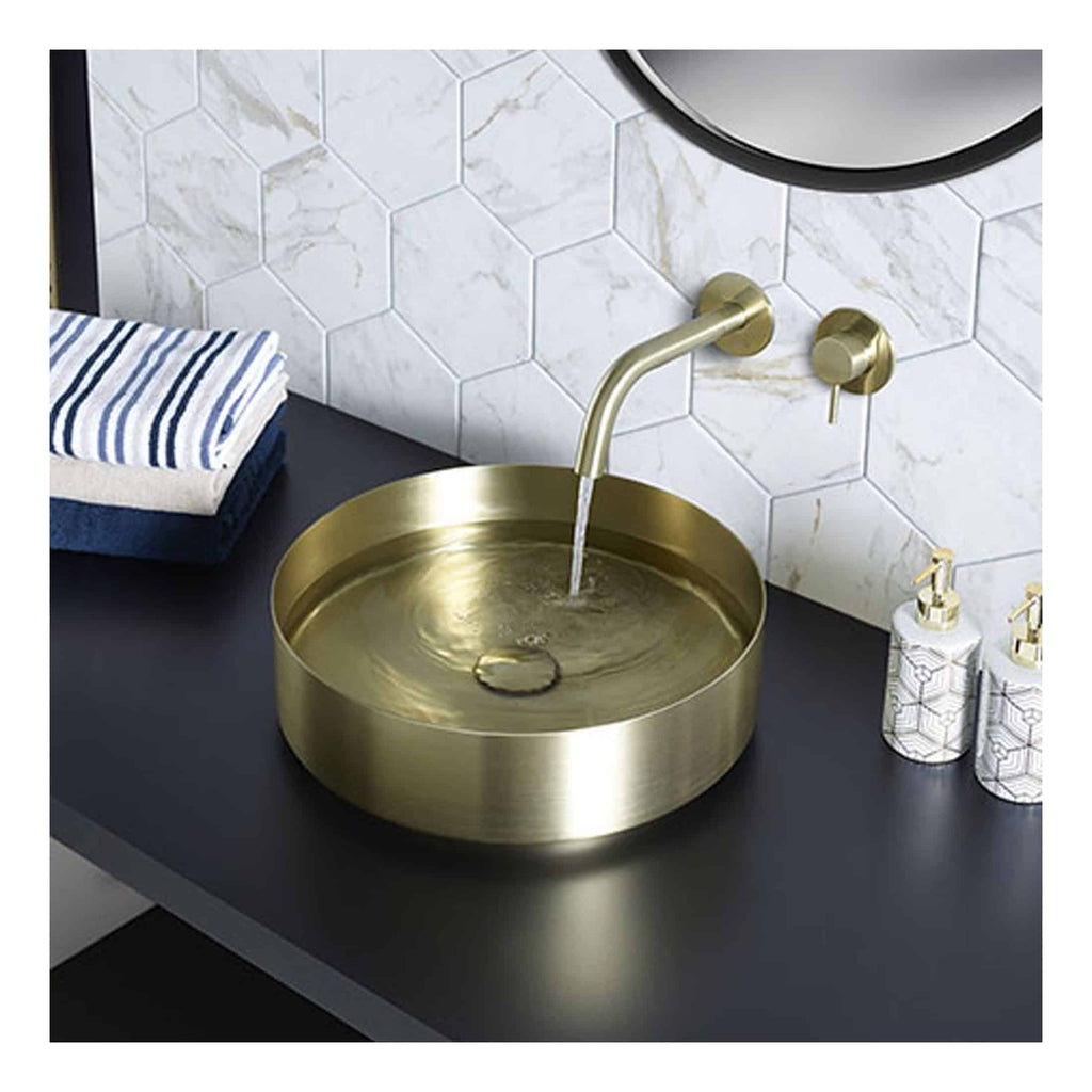 Sleek gold bathroom sink with modern fixtures, set against a stylish white hexagonal tiled wall, creating a luxurious and contemporary bathroom aesthetic.