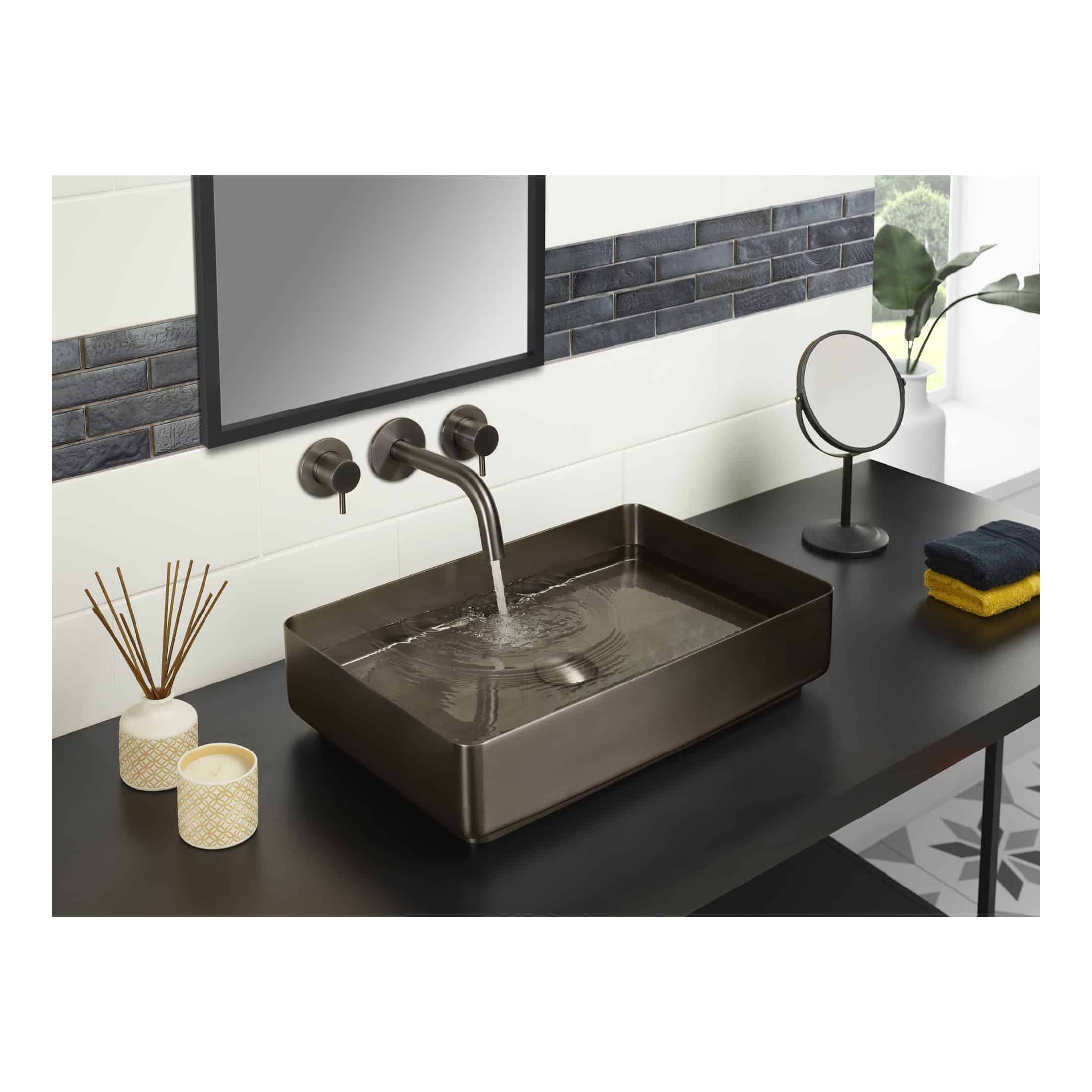 Sleek rectangular bathroom sink in matte black with modern metallic tap and wall-mounted controls, set against a stylish tiled wall in a contemporary bathroom space.