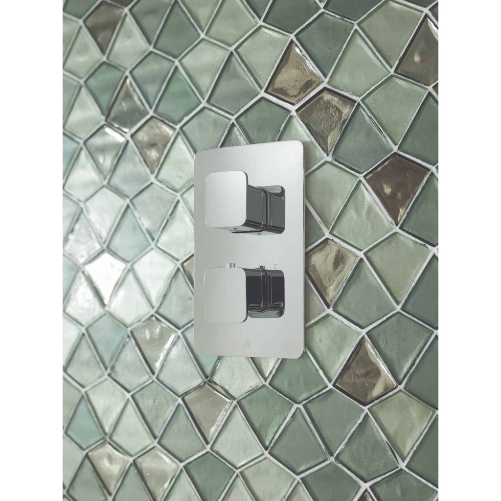 Sleek modern bathroom light switch with chrome finish installed on a colourful mosaic tile wall.