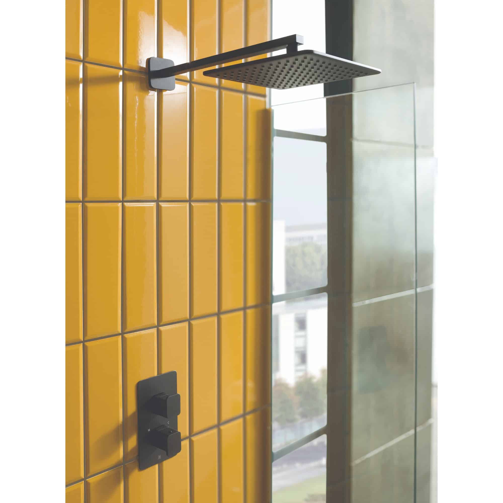 Modern black square rainfall shower head and wall mixer taps in yellow tiled bathroom, contemporary bathroom shower design, high-quality bathroom fixtures, stylish modern bathroom decor.