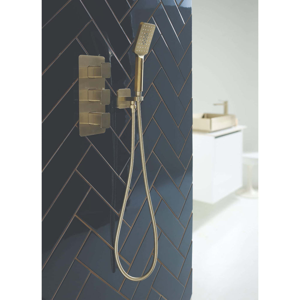 Contemporary gold shower head and fixtures with black herringbone tiled wall in modern bathroom design.