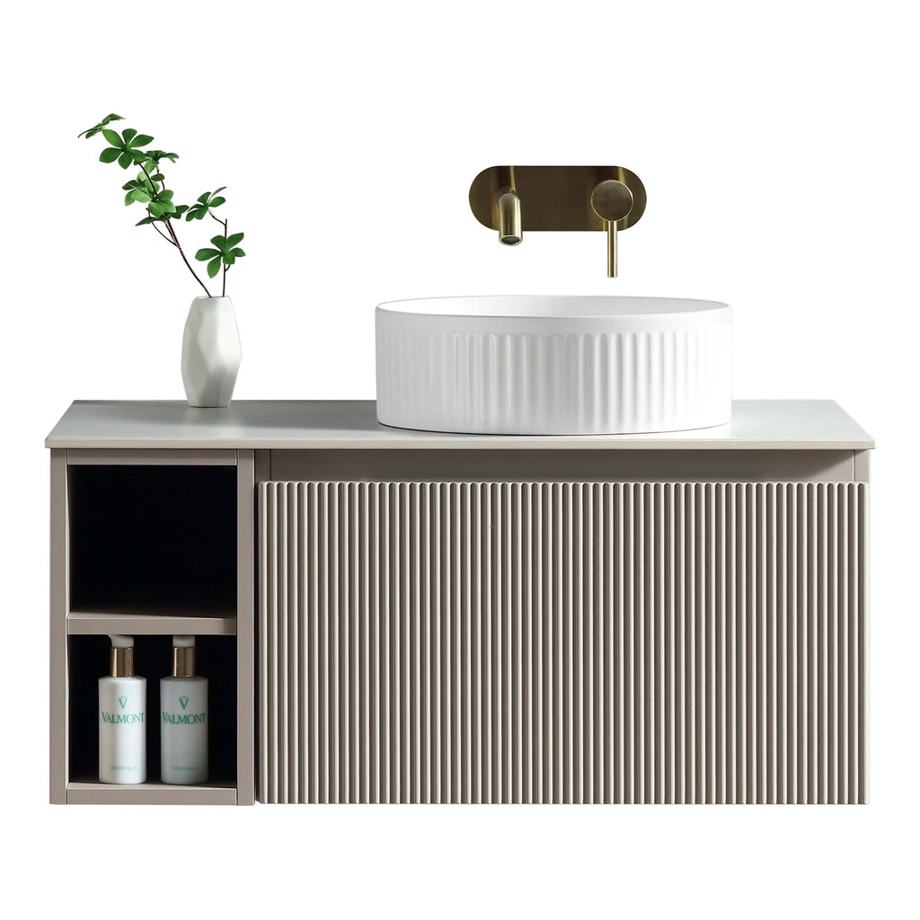 White modern bathroom vanity unit with a ribbed basin, gold wall-mounted tap, and minimalist decor, ideal for contemporary bathroom design and fixtures.