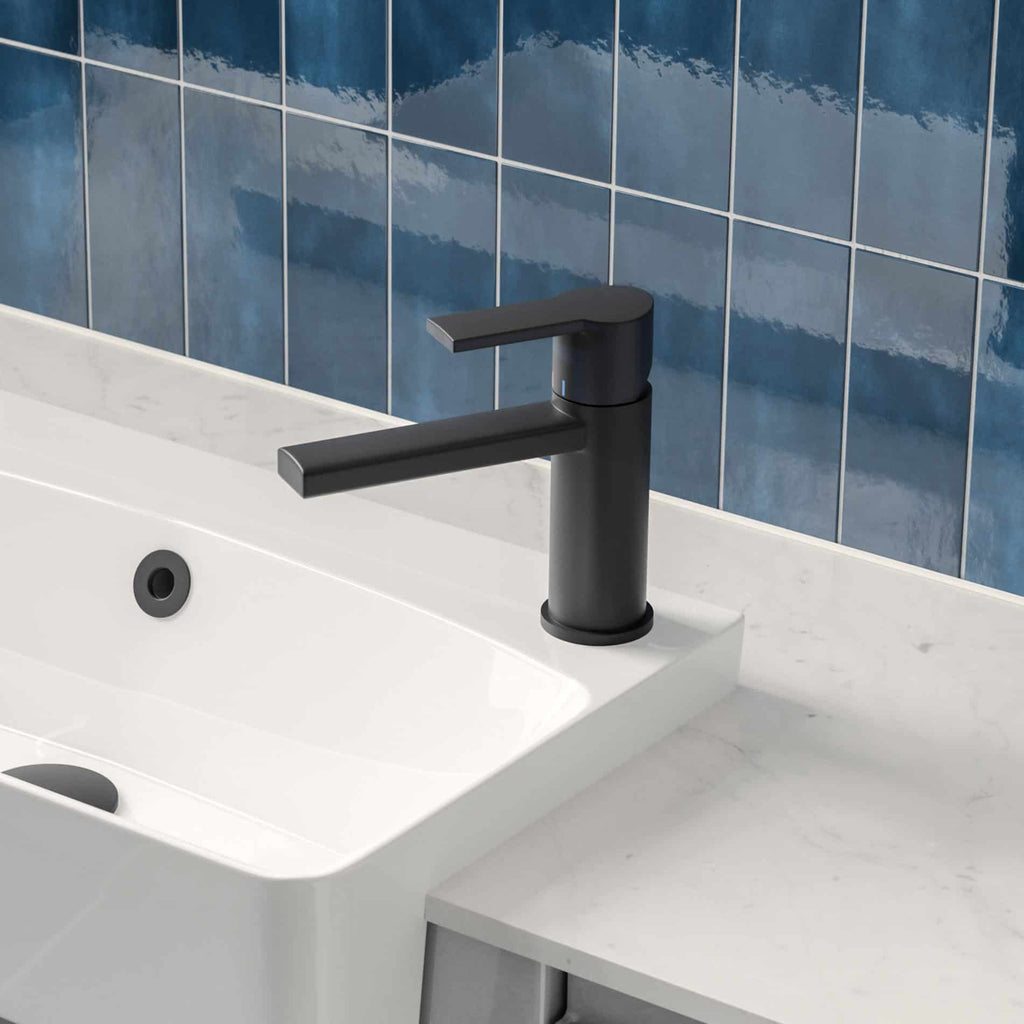 Sleek black bathroom sink mixer tap in modern design, mounted on a white ceramic basin with a marble countertop, set against a vibrant blue tiled wall, ideal for contemporary bathroom renovations.