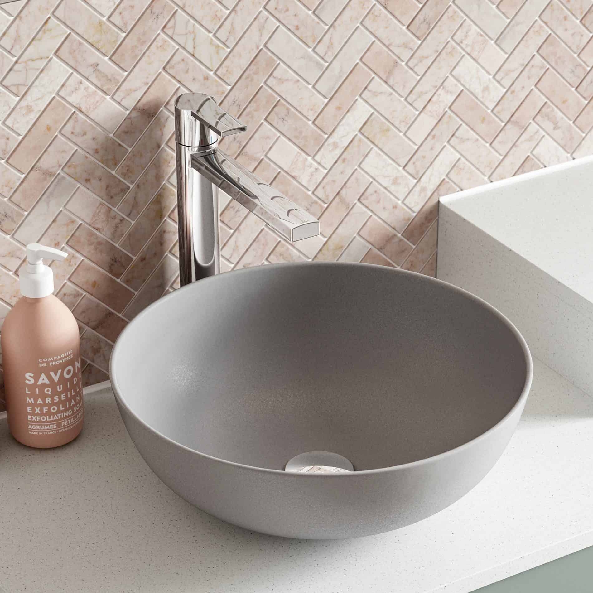 Contemporary grey bathroom sink with a modern chrome tap and pink mosaic tile backsplash, featuring a minimalist design for stylish bathroom decor.