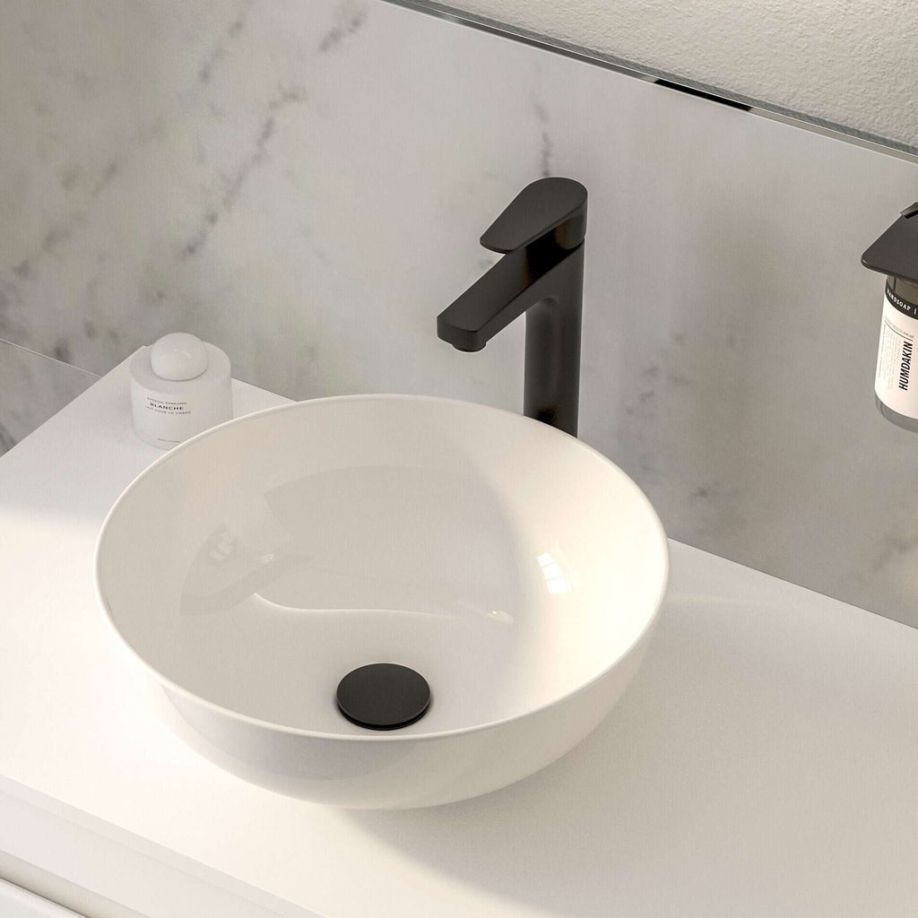 Contemporary white vessel bathroom sink with matte black faucet on a sleek white vanity with modern décor.