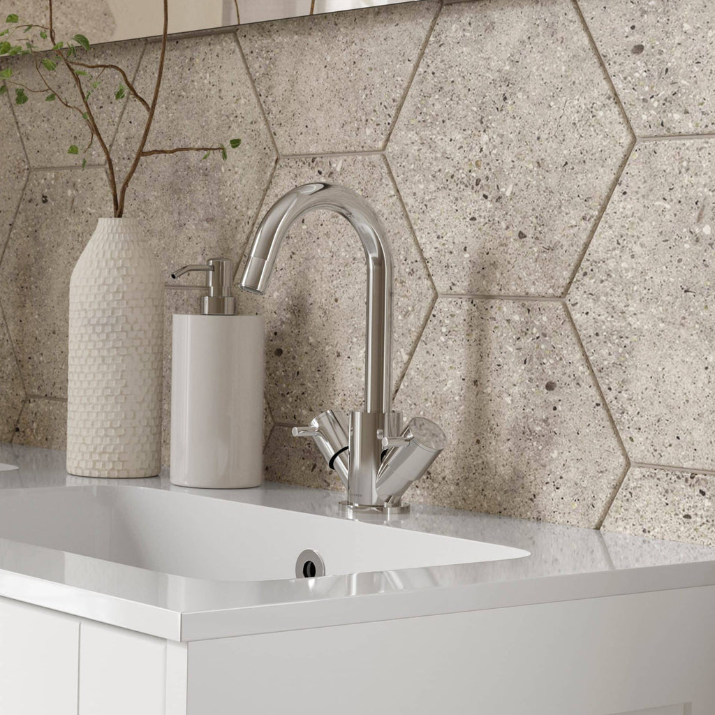 Modern kitchen sink with chrome tap, soap dispenser, and decorative vase on white countertop against textured hexagonal tile wall.