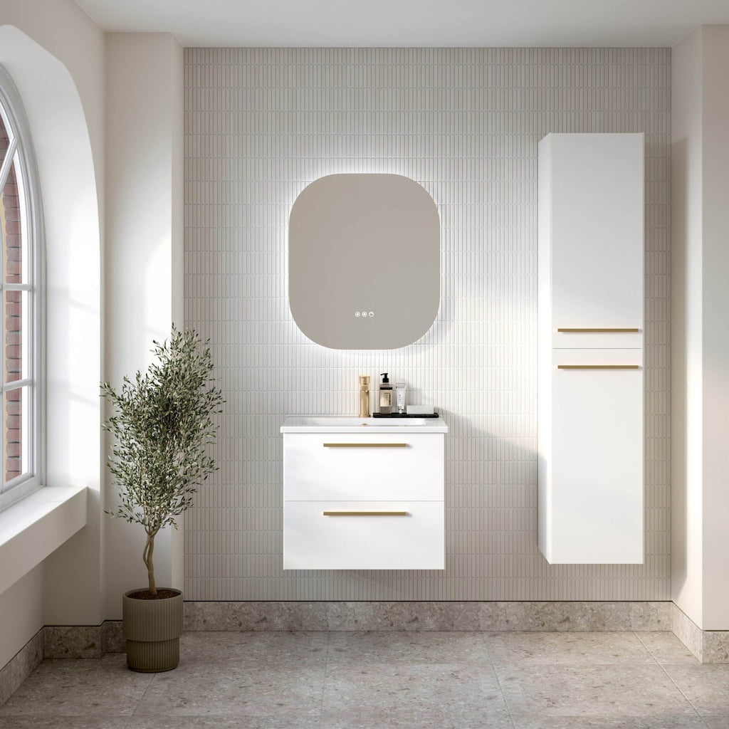 Contemporary white bathroom vanity with storage drawers, mounted on a textured beige tiled wall beneath an illuminated round mirror, complemented by a tall white cupboard and a potted plant near a window.