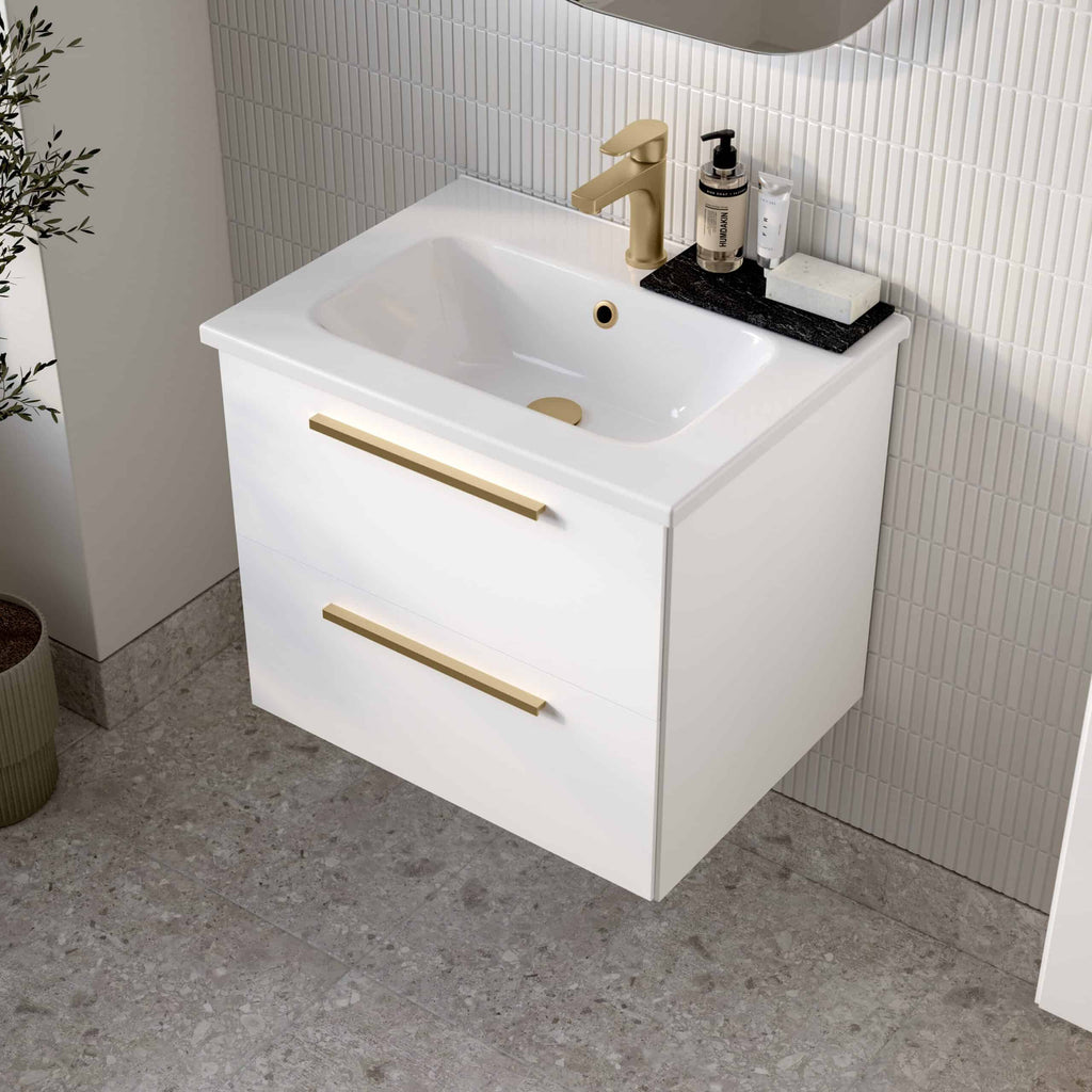 Contemporary white bathroom vanity with integrated sink, featuring sleek gold handles and fixtures, set against modern tiled walls, perfect for stylish bathroom renovations.