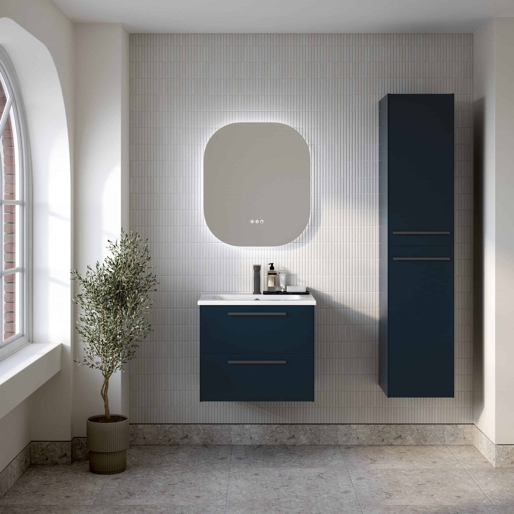 Sleek navy blue bathroom vanity with integrated sink, modern oval mirror with backlit illumination, tall storage cabinet, and natural light from large window, creating a contemporary and stylish bathroom space.