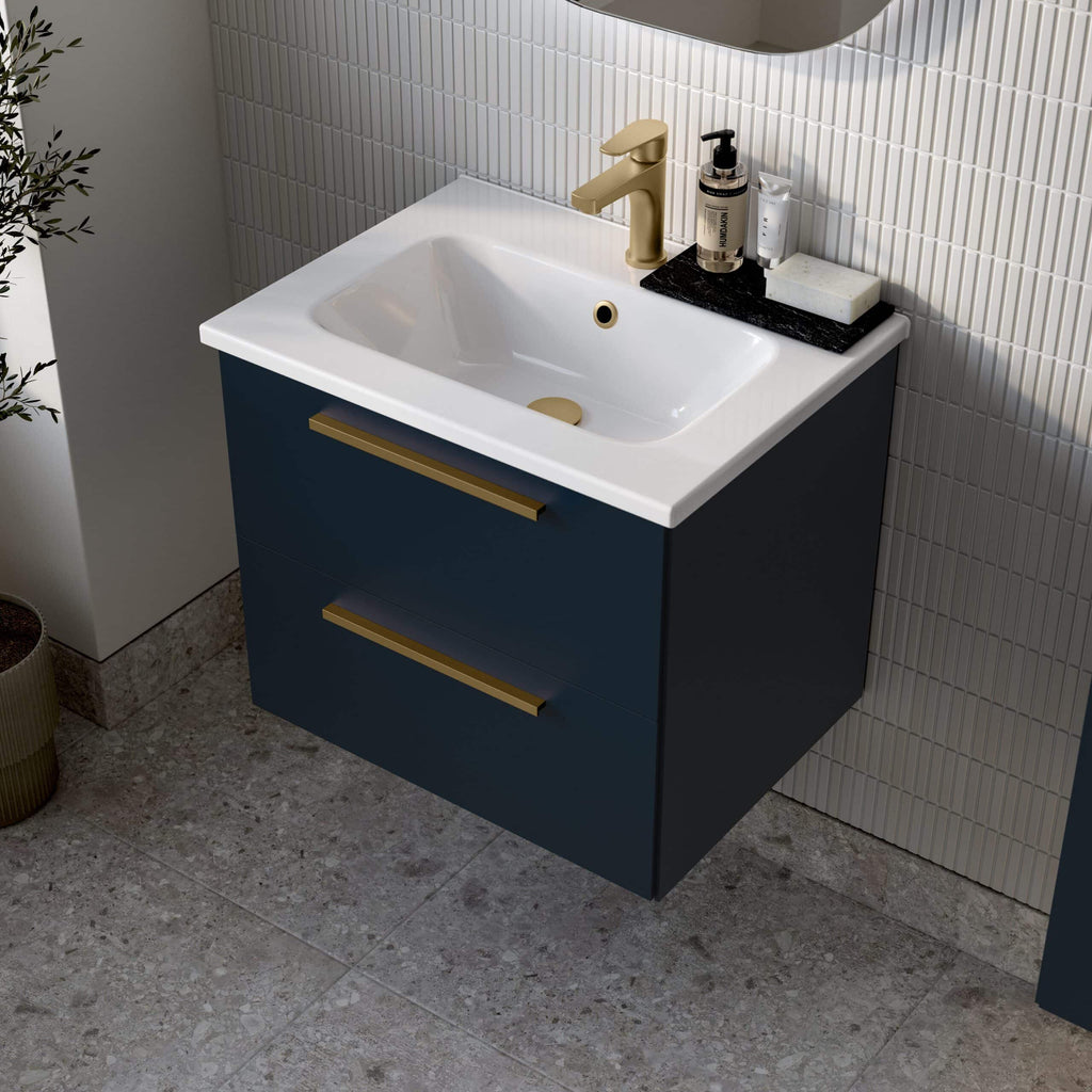 Sleek navy blue bathroom vanity with a white ceramic sink and gold fixtures, featuring two spacious drawers with modern gold handles, set against textured tiled walls for a contemporary look.