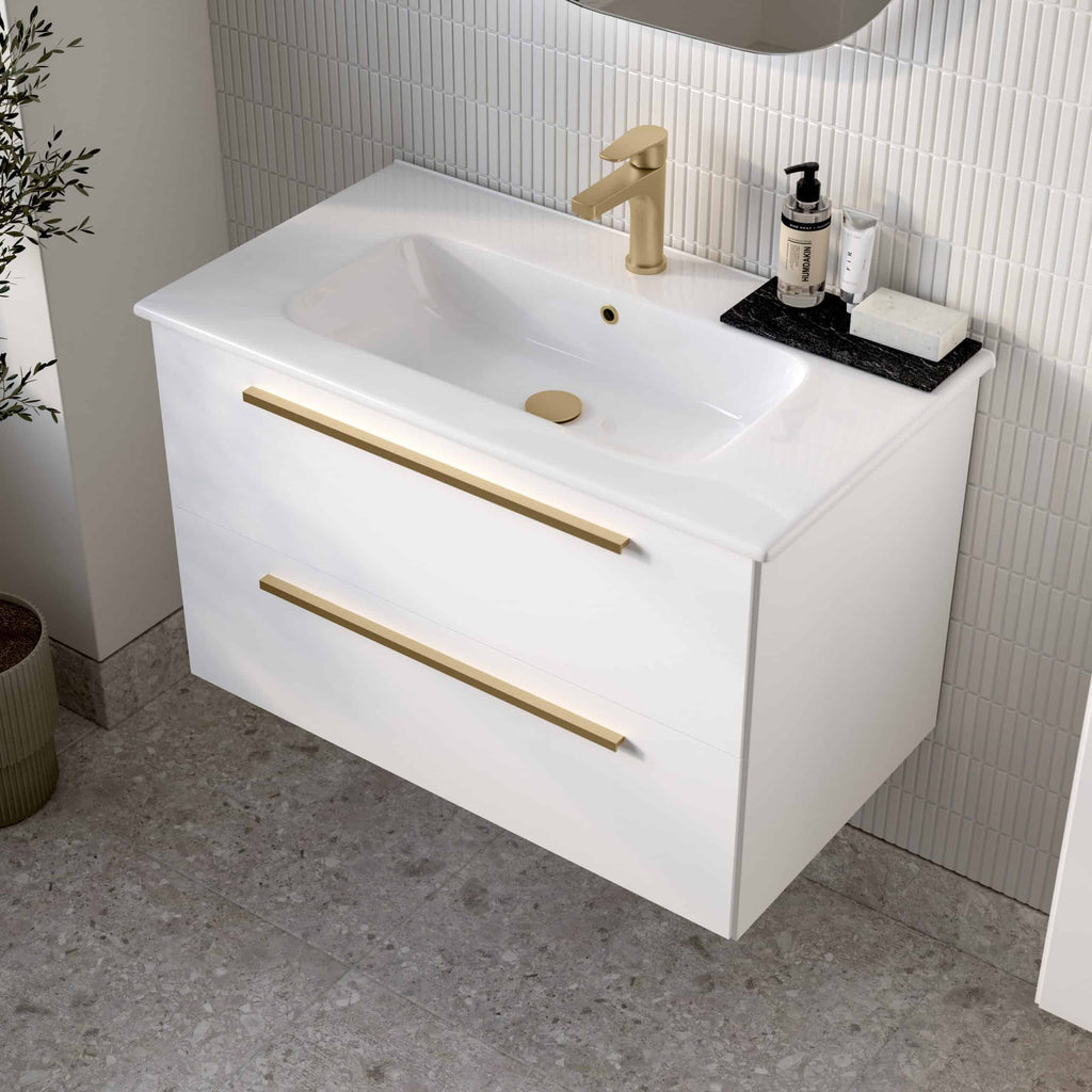 Sleek modern white bathroom vanity with gold handles and built-in sink, perfect for contemporary Bubly bathrooms. Featuring stylish gold faucet and accessories on black marble tray.