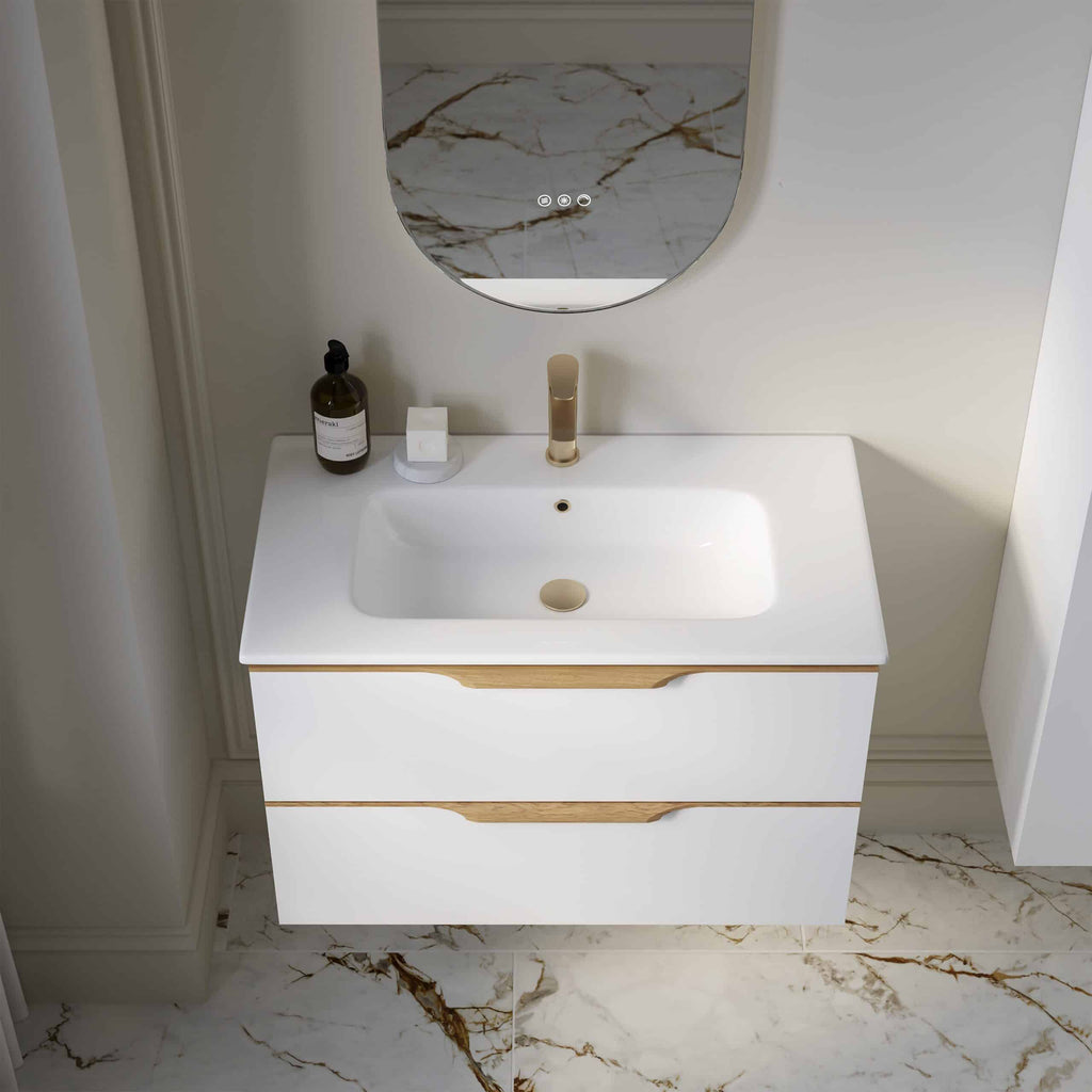 Sleek modern bathroom vanity with white finish and wooden accents, featuring a stylish under-mount sink and gold fixtures, set against a marble wall for luxury bathroom design.