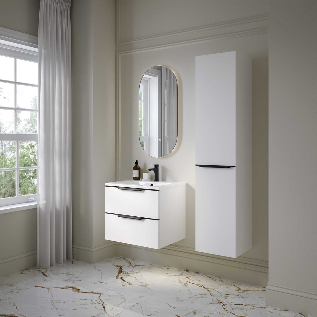 Modern white bathroom vanity unit with dual drawers, sleek black handles, and a compact black faucet, complemented by an oval mirror and tall storage cabinet in a bright, minimalist bathroom setting.