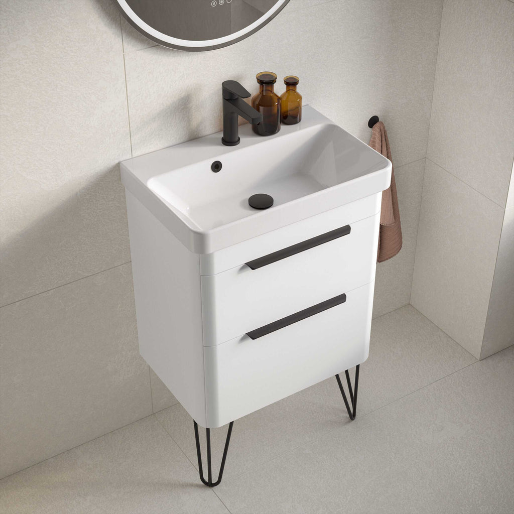 Modern white bathroom vanity unit with black handles and hairpin legs, fitted with a stylish rectangular sink, black faucet, and amber soap dispensers, ideal for contemporary bathroom decor.