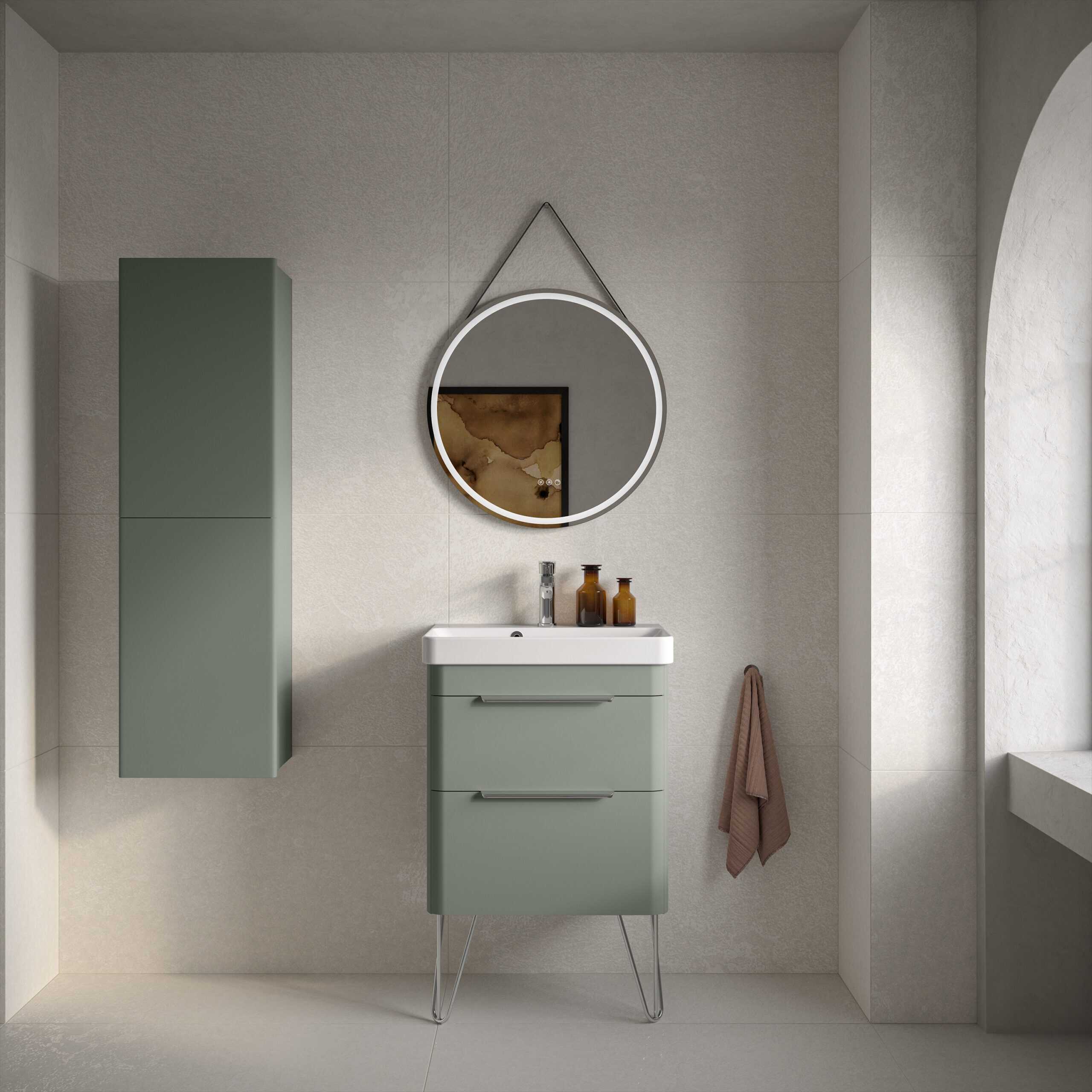 Sleek modern green bathroom vanity with matching wall-mounted storage cabinet, stylish round mirror with LED lighting, neutral wall tiles, and a soft brown towel, creating a contemporary and functional bathroom space.