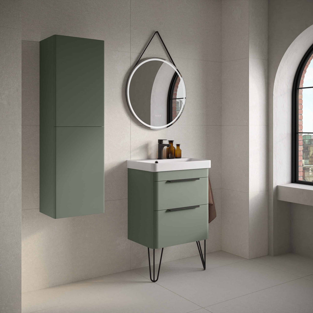 Sleek modern green bathroom vanity with two drawers, wall-mounted tall cabinet, round mirror with LED lighting, and natural light from large arched window, creating a stylish and functional bathroom space.