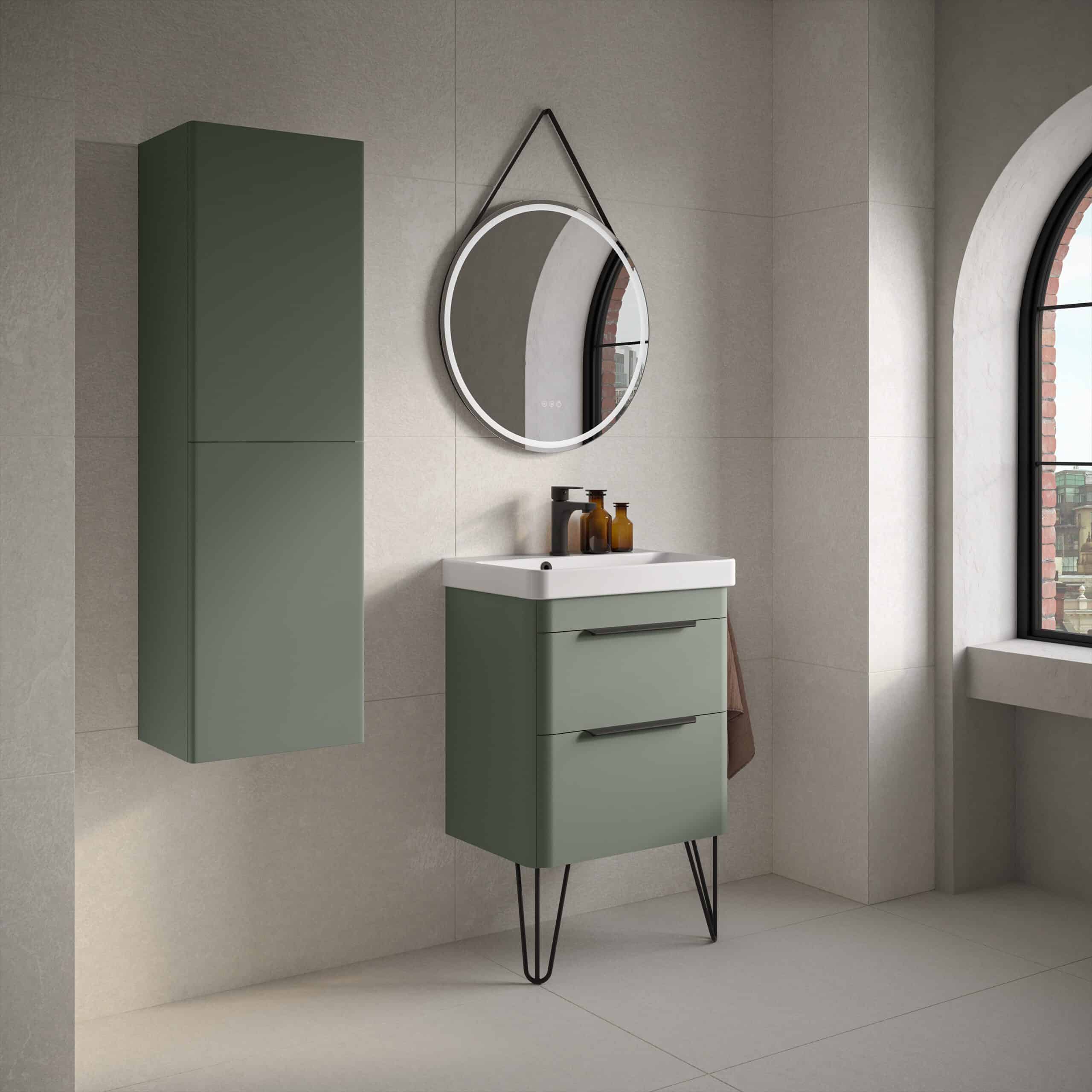 Sleek modern green bathroom vanity with two drawers, wall-mounted tall cabinet, round mirror with LED lighting, and natural light from large arched window, creating a stylish and functional bathroom space.