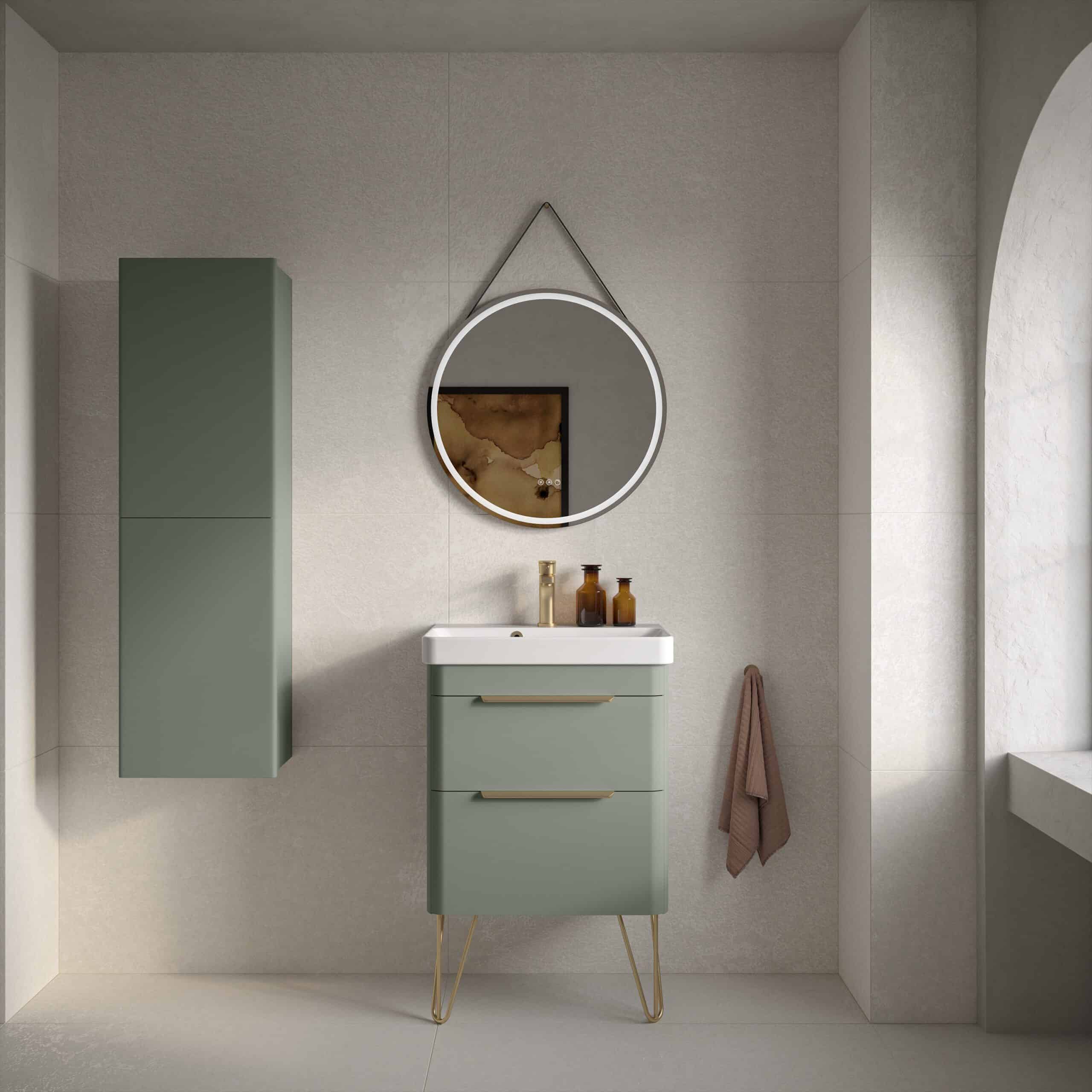 Sleek green bathroom vanity with modern gold handles and matching wall cabinet, minimalist round mirror with LED lighting, soft beige wall tiles, and a warm-toned towel for contemporary bathroom design.