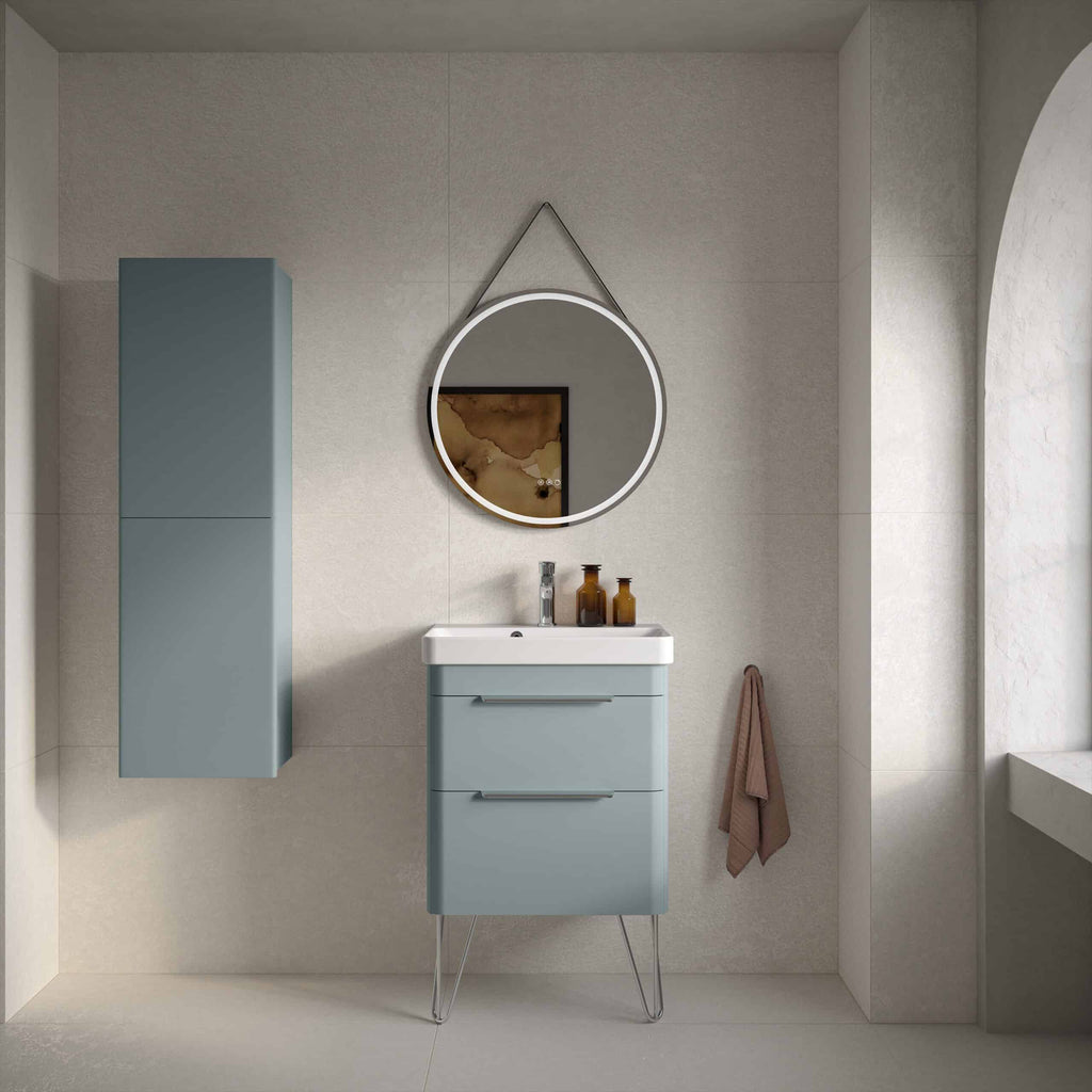 Stylish modern bathroom featuring a blue vanity unit with sleek drawers, a matching tall storage cabinet, and a round illuminated mirror, creating a contemporary and minimalist bathroom design.