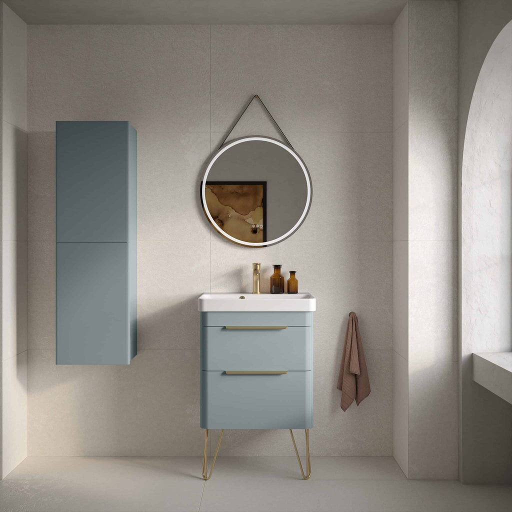 Modern blue bathroom vanity with matching wall cabinet, round lit mirror, and elegant decor, showcasing contemporary bathroom design with stylish fixtures and neutral tones.