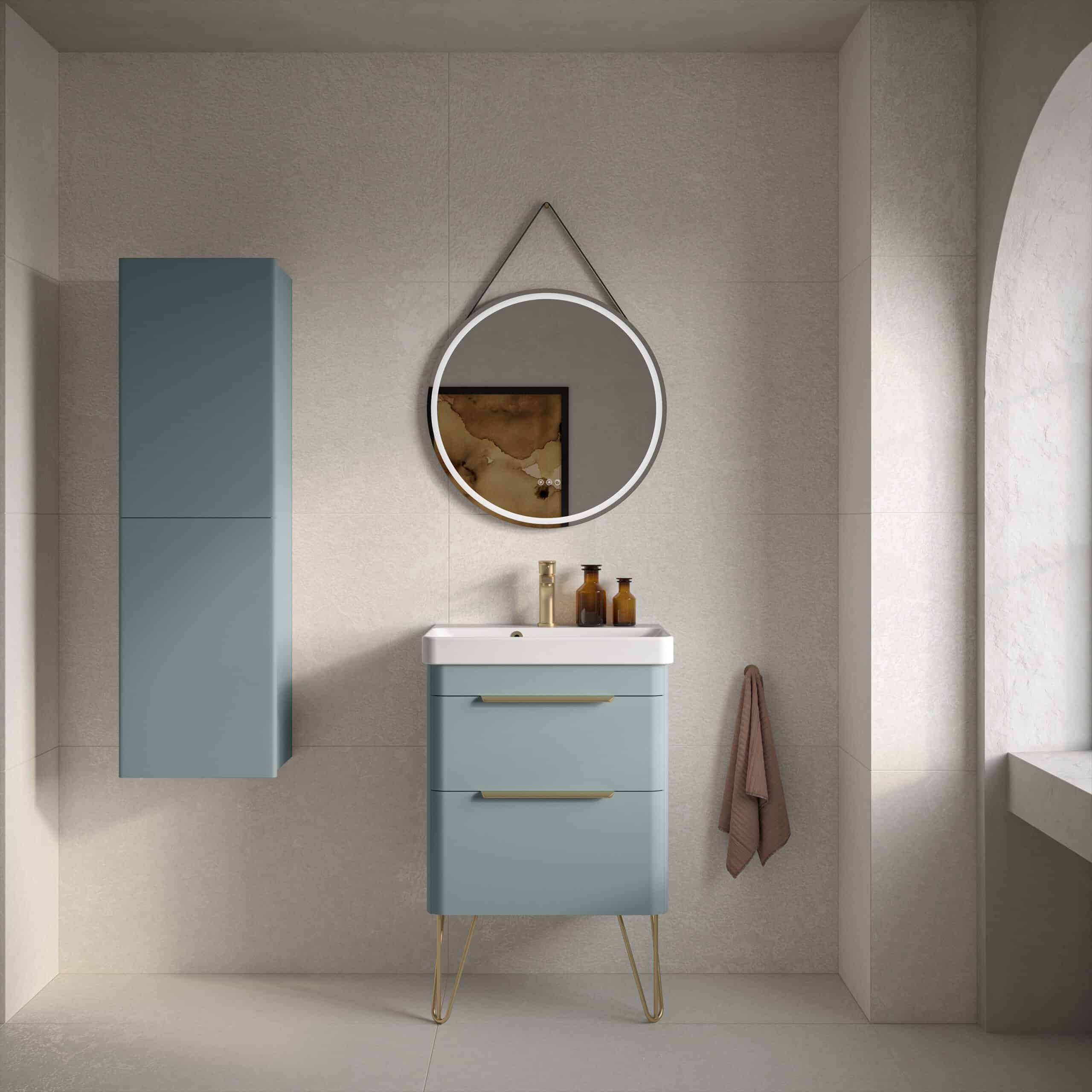 Modern blue bathroom vanity with matching wall cabinet, round lit mirror, and elegant decor, showcasing contemporary bathroom design with stylish fixtures and neutral tones.