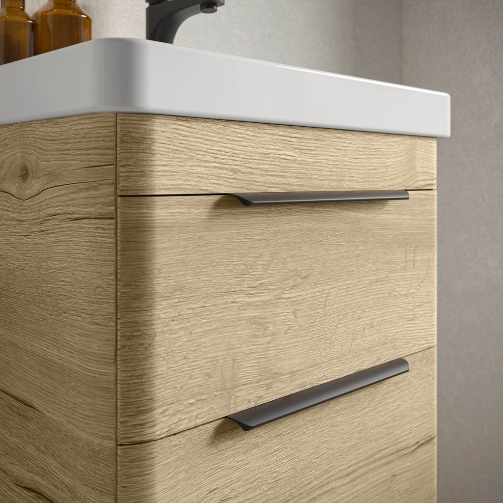 Sleek modern bathroom vanity cabinet with natural wood finish and streamlined grey handles, featuring a white ceramic sink for contemporary bathroom design.