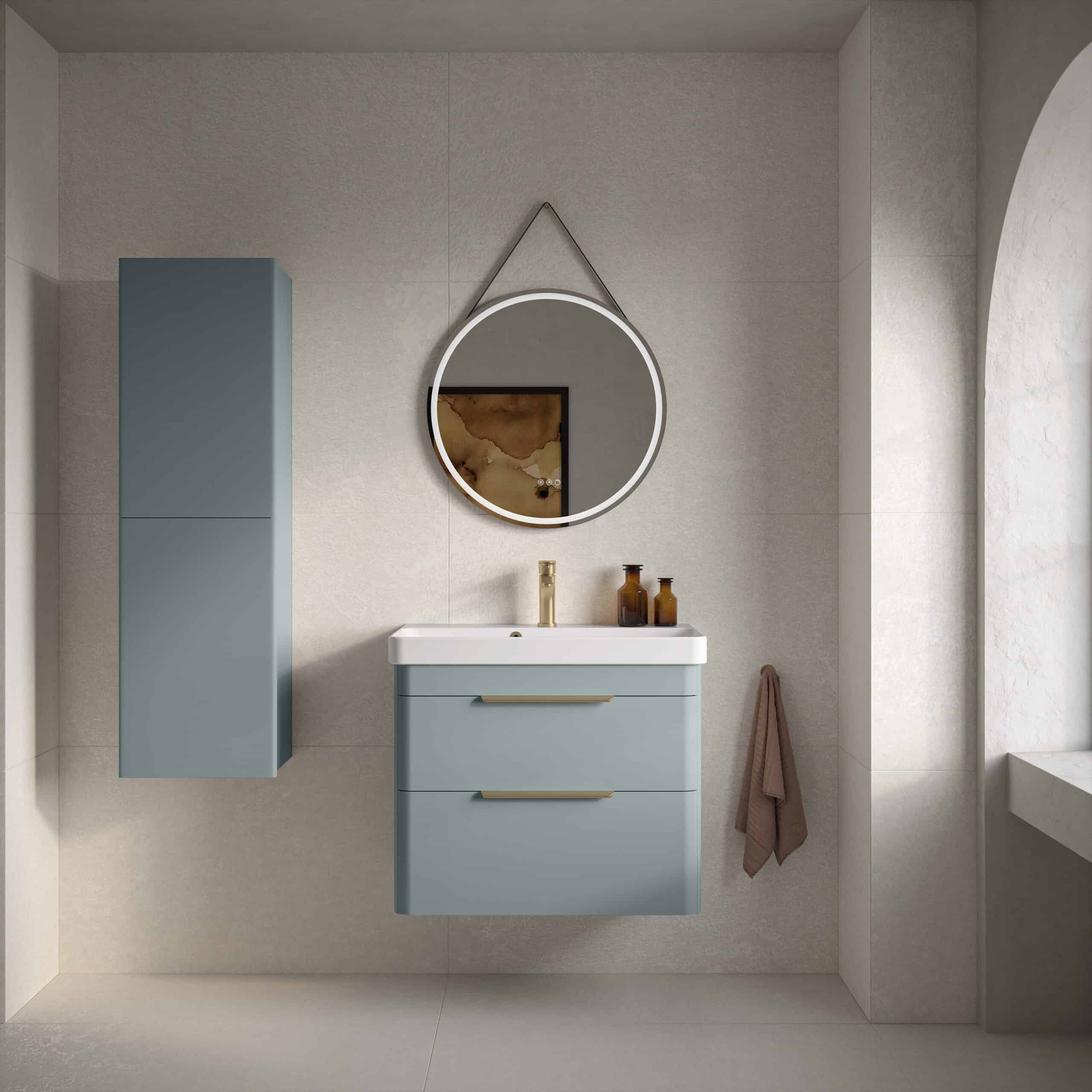 Modern blue bathroom vanity with integrated sink and brass hardware, wall-mounted cabinet, stylish round mirror with LED lighting, and beige tiled walls for a contemporary bathroom design.