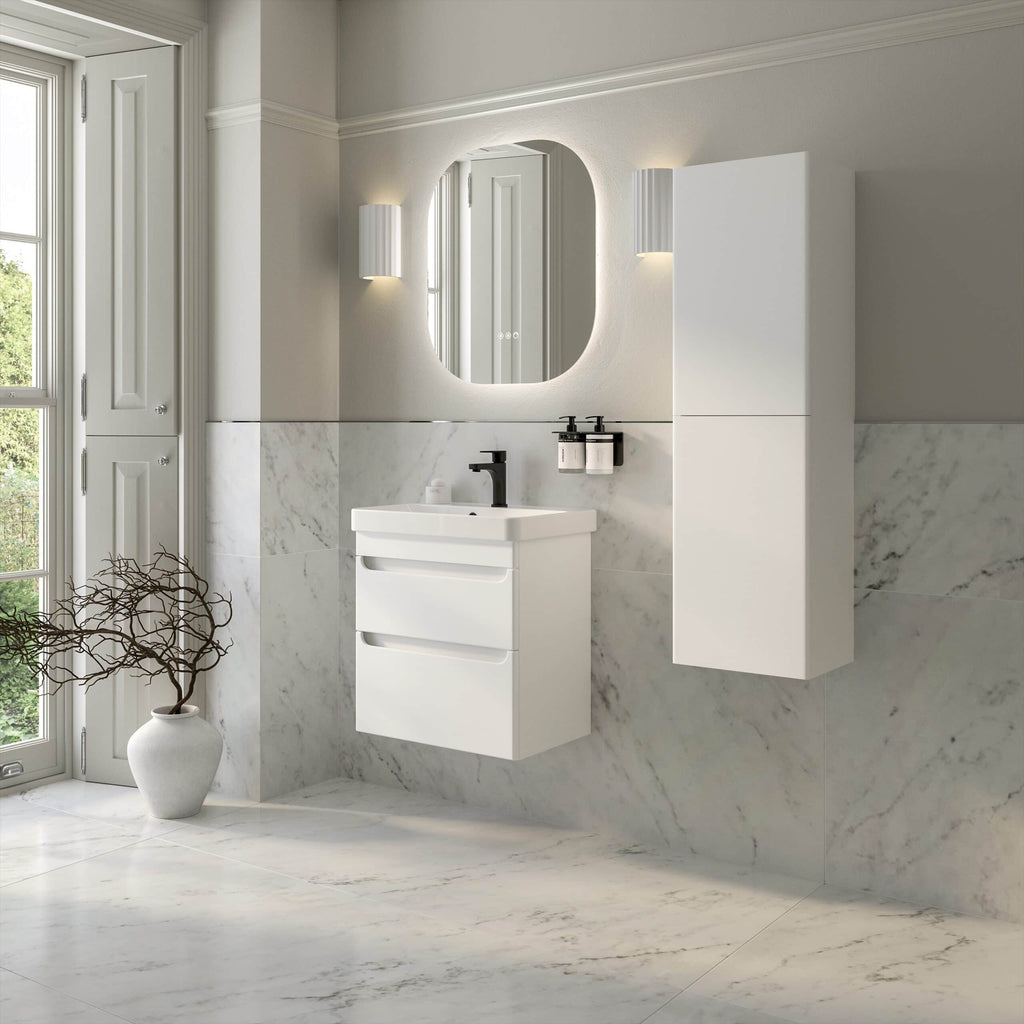 Sleek modern white bathroom vanity with drawers and a black faucet, mounted on a marble wall in a bright, contemporary bathroom with a large mirror and wall-mounted storage cabinet.
