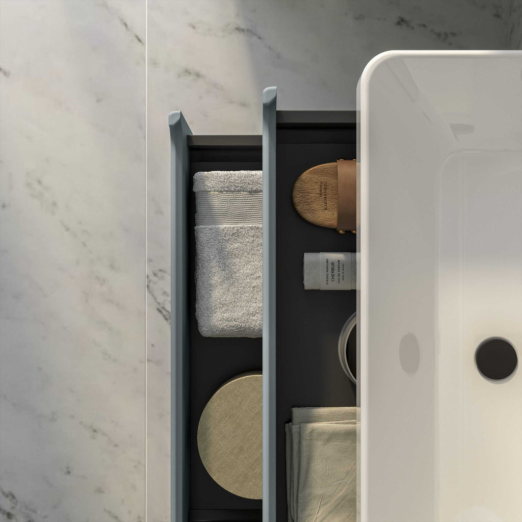 Neatly organised bathroom drawer with towels, toiletries, and accessories for modern bathroom storage solutions.