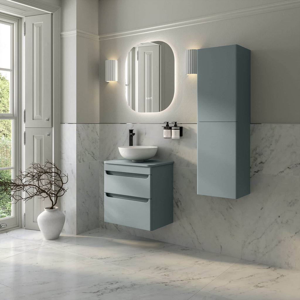 Sleek blue bathroom vanity unit with a round vessel sink, wall-mounted storage cabinet, and modern mirror in a bright, marble-tiled bathroom with natural light.