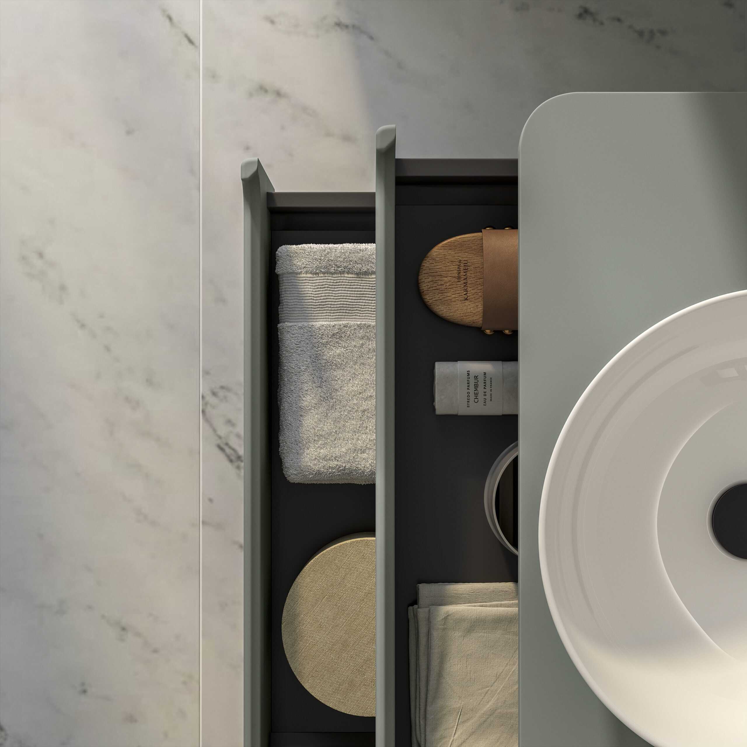 Luxurious bathroom accessories including a white towel, bamboo soap dish, skincare products, and beige cloth on a sleek dark grey side table with a modern white sink.