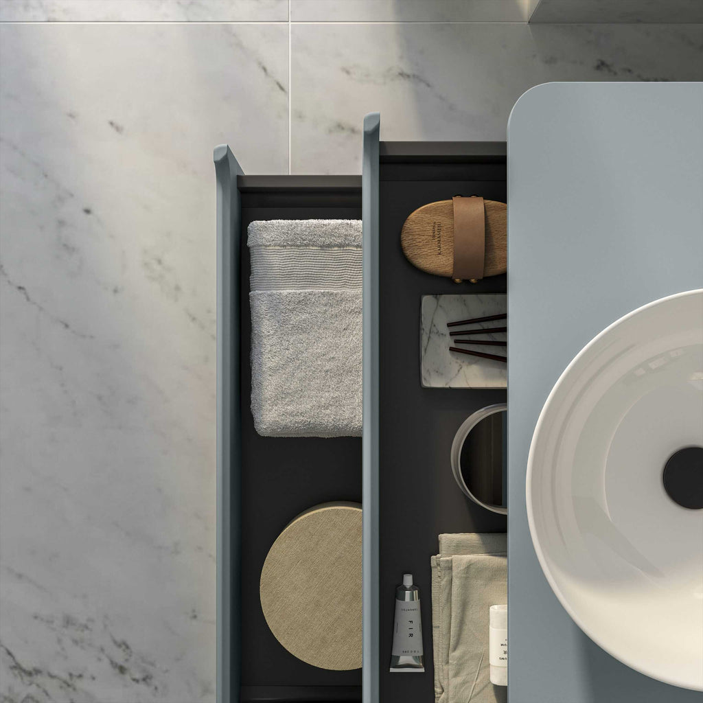 Soft grey bathroom drawer with neatly arranged towels, skincare products, and accessories, showcasing modern bathroom organisation and design.