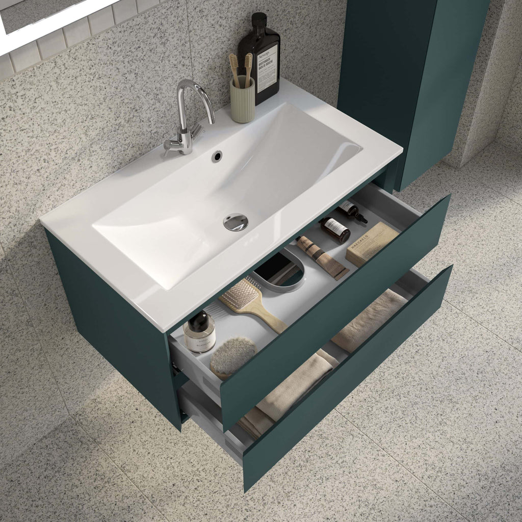 Modern teal bathroom vanity with open drawers containing toiletries and accessories, under a sleek white sink with chrome tap, set against textured wall and tiled floor.