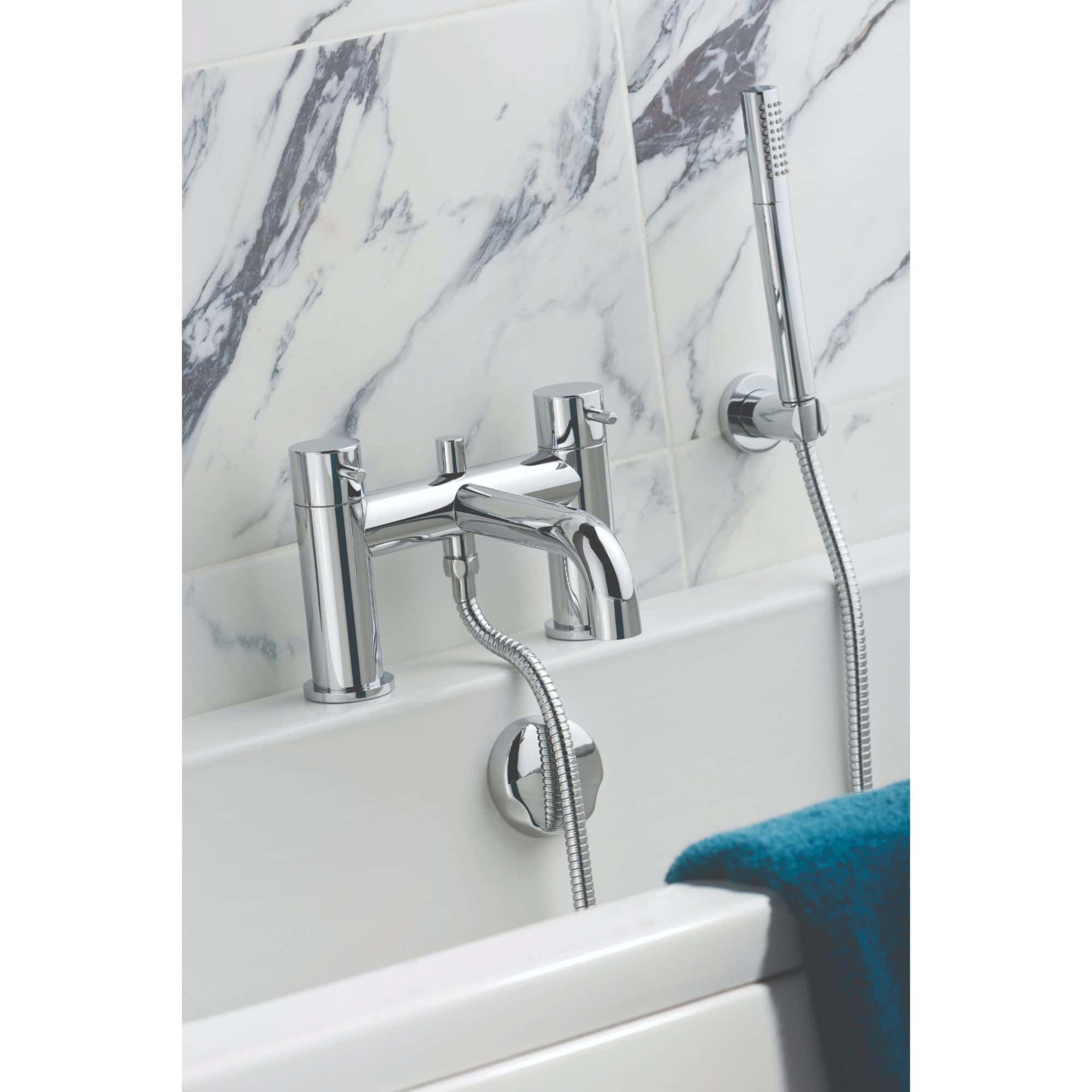 Polished chrome bathroom mixer tap with handheld shower attachment, set against a marble tiled wall, designed for modern and stylish bathroom interiors.
