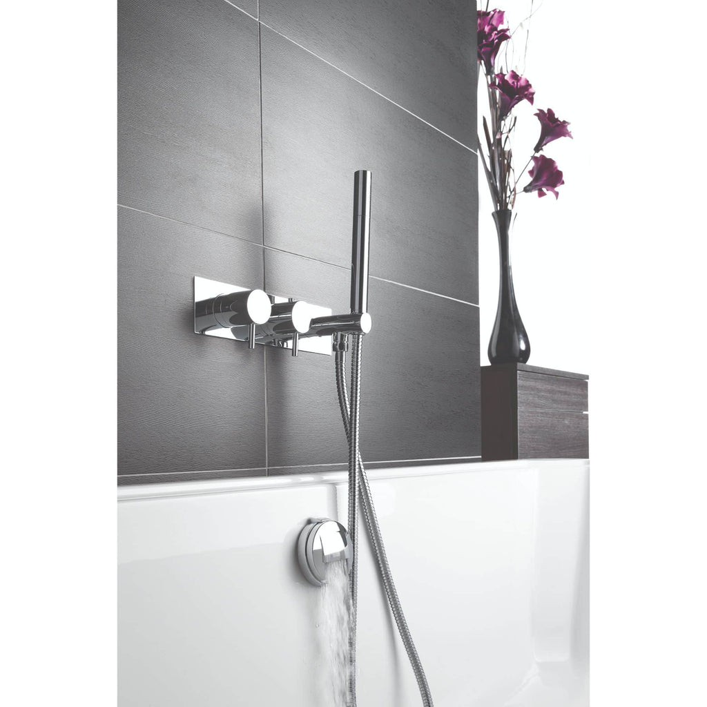 Sleek modern bathroom shower with chrome fittings and a handheld showerhead, featuring a stylish grey tiled wall and decorative vase with purple flowers in the background.