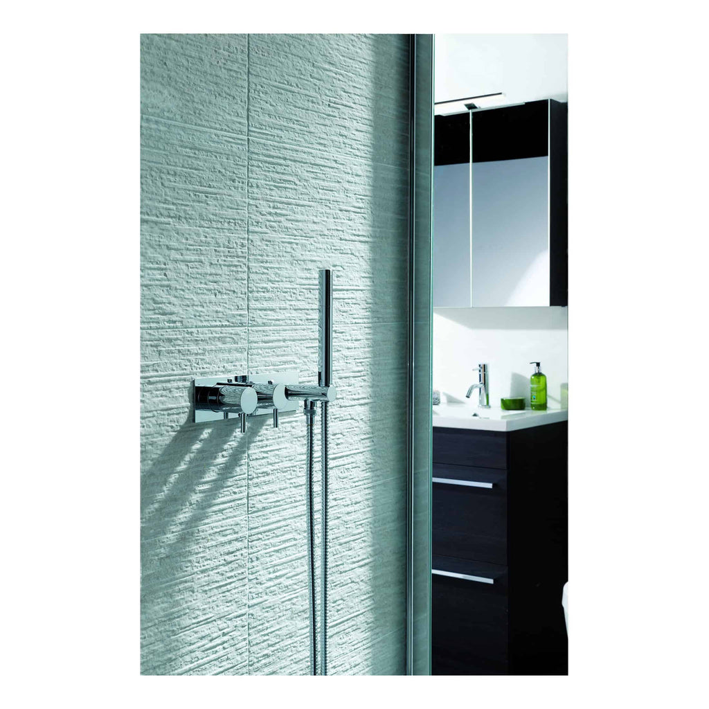 Chrome bathroom shower mixer and handheld shower head in a modern shower enclosure.