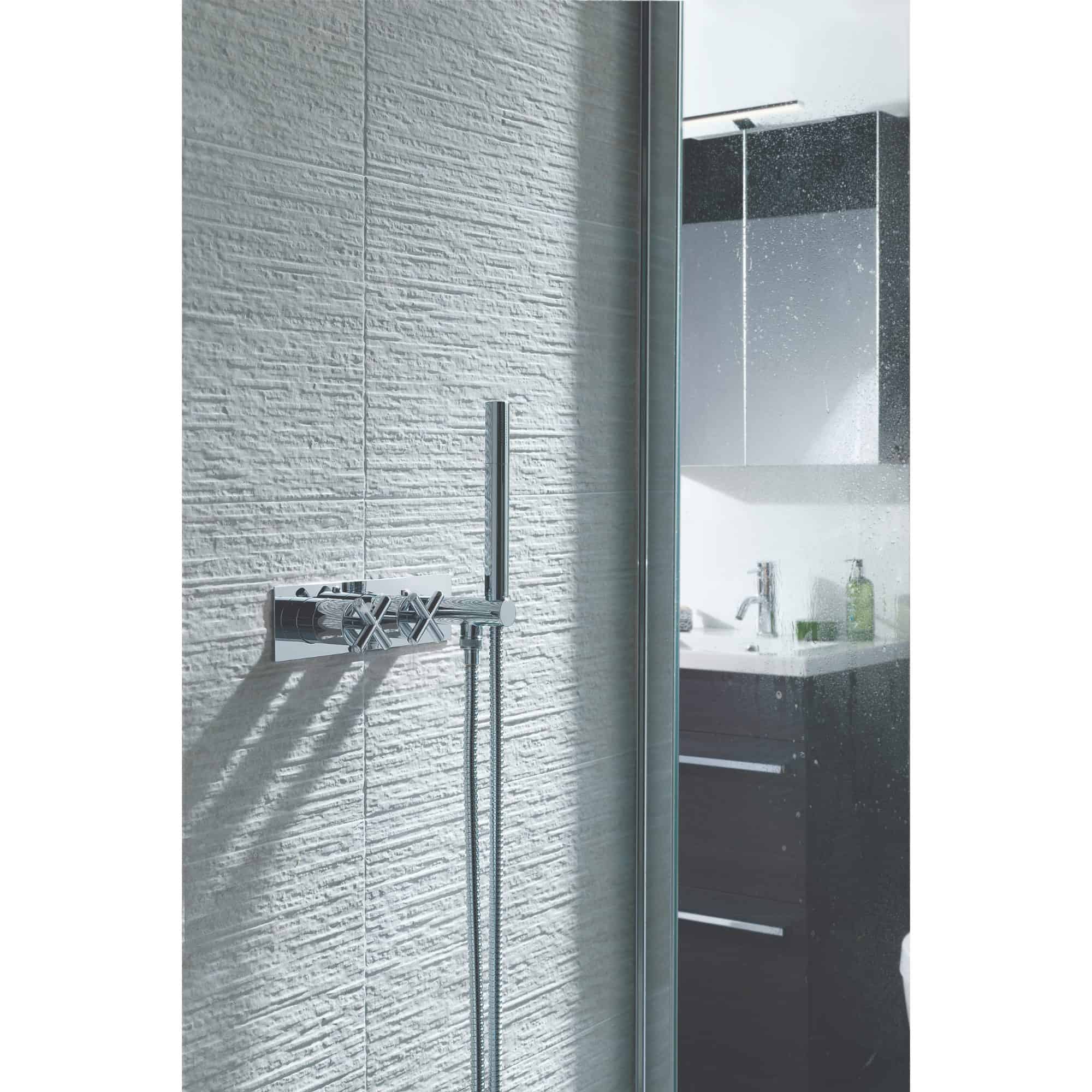 Modern chrome wall-mounted shower fixture with adjustable hand shower in a contemporary bathroom setting.