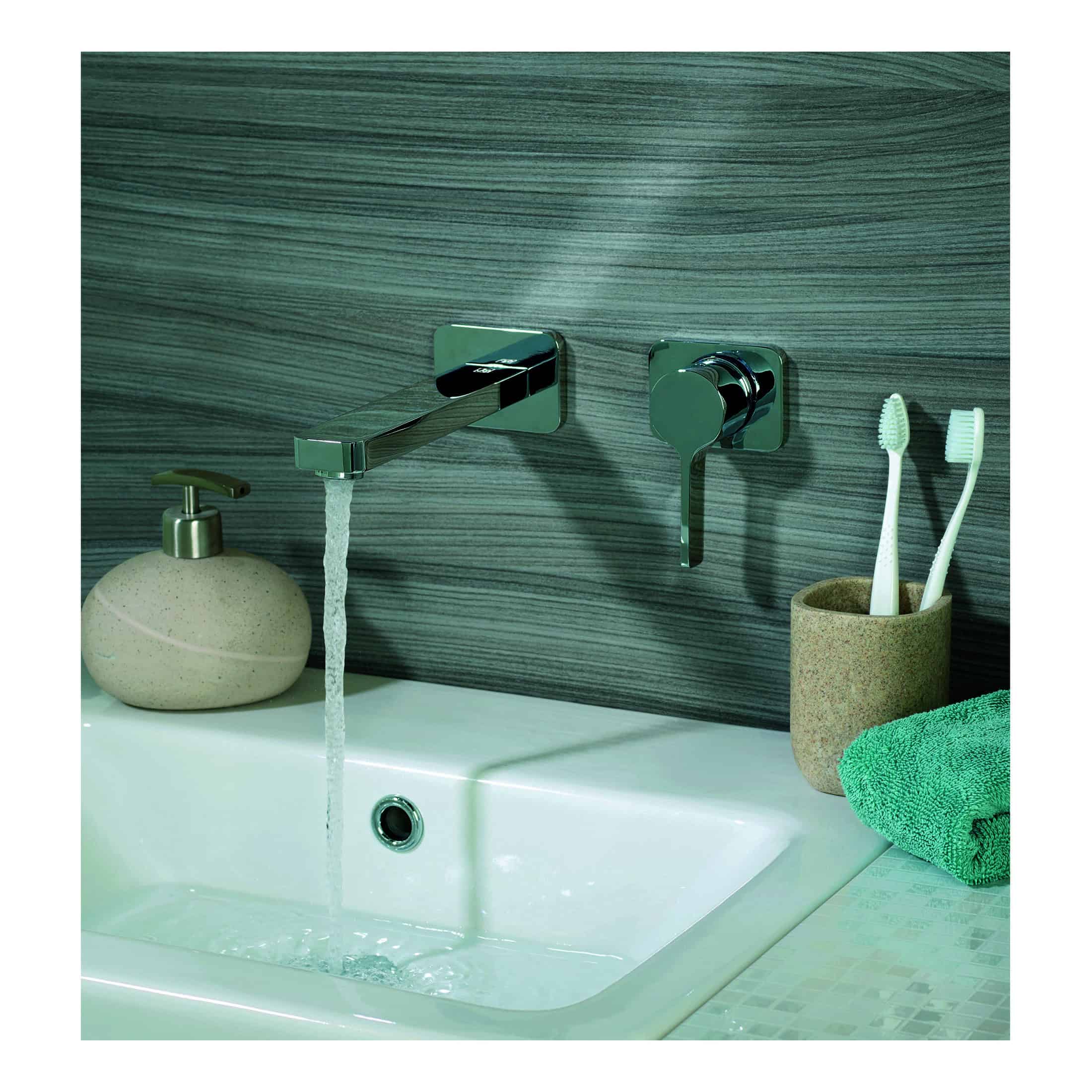 Sleek modern chrome bathroom tap and wall-mounted fixtures with a white ceramic sink, toothbrush holder, and soft green towel, perfect for contemporary bathroom design and hygiene.