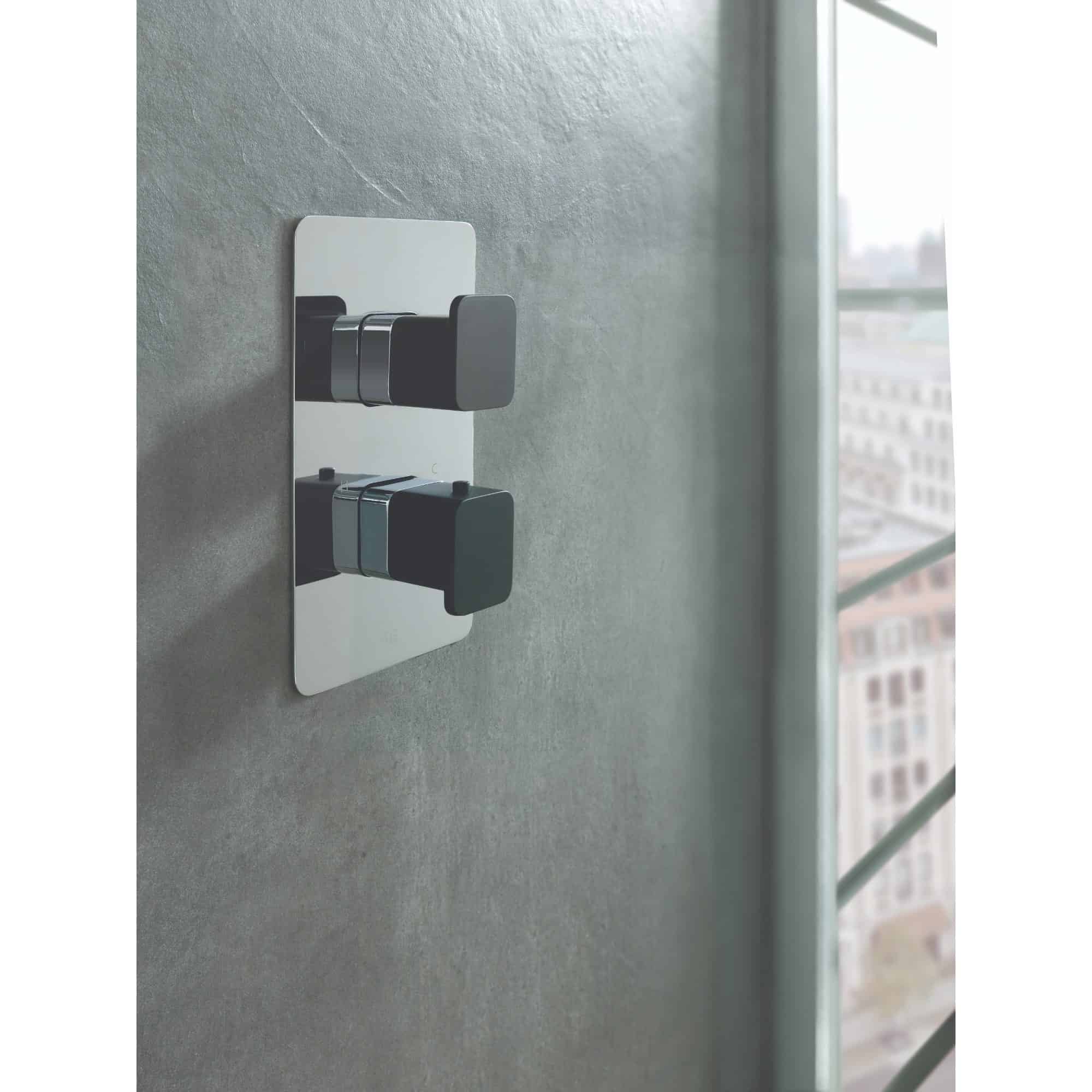 Sleek modern black and silver light switch on a textured grey wall in a contemporary bathroom setting.