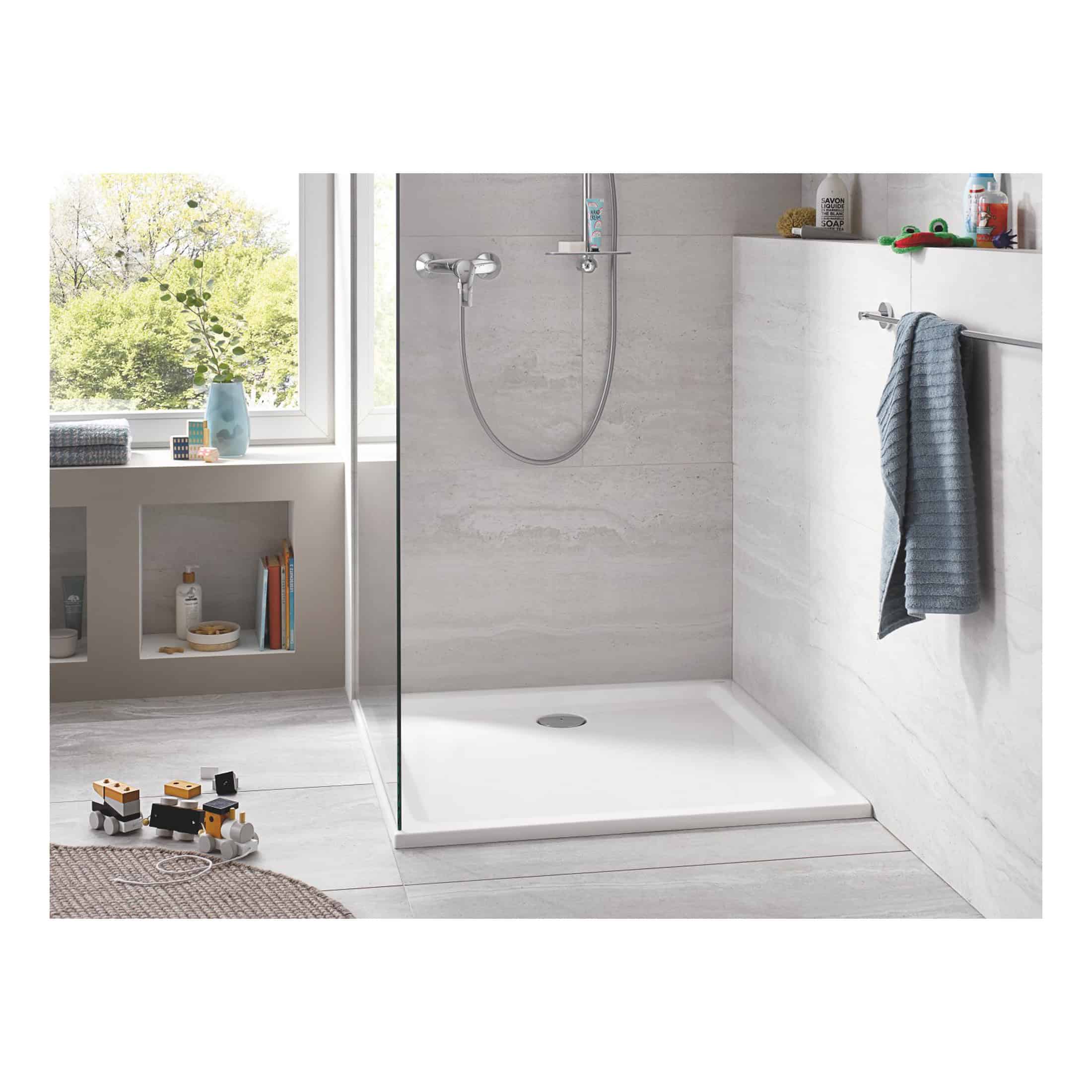Shower area with a modern, minimalist design featuring a walk-in shower with a handheld showerhead, light grey marble walls, and a white shower tray, ideal for contemporary bathrooms.